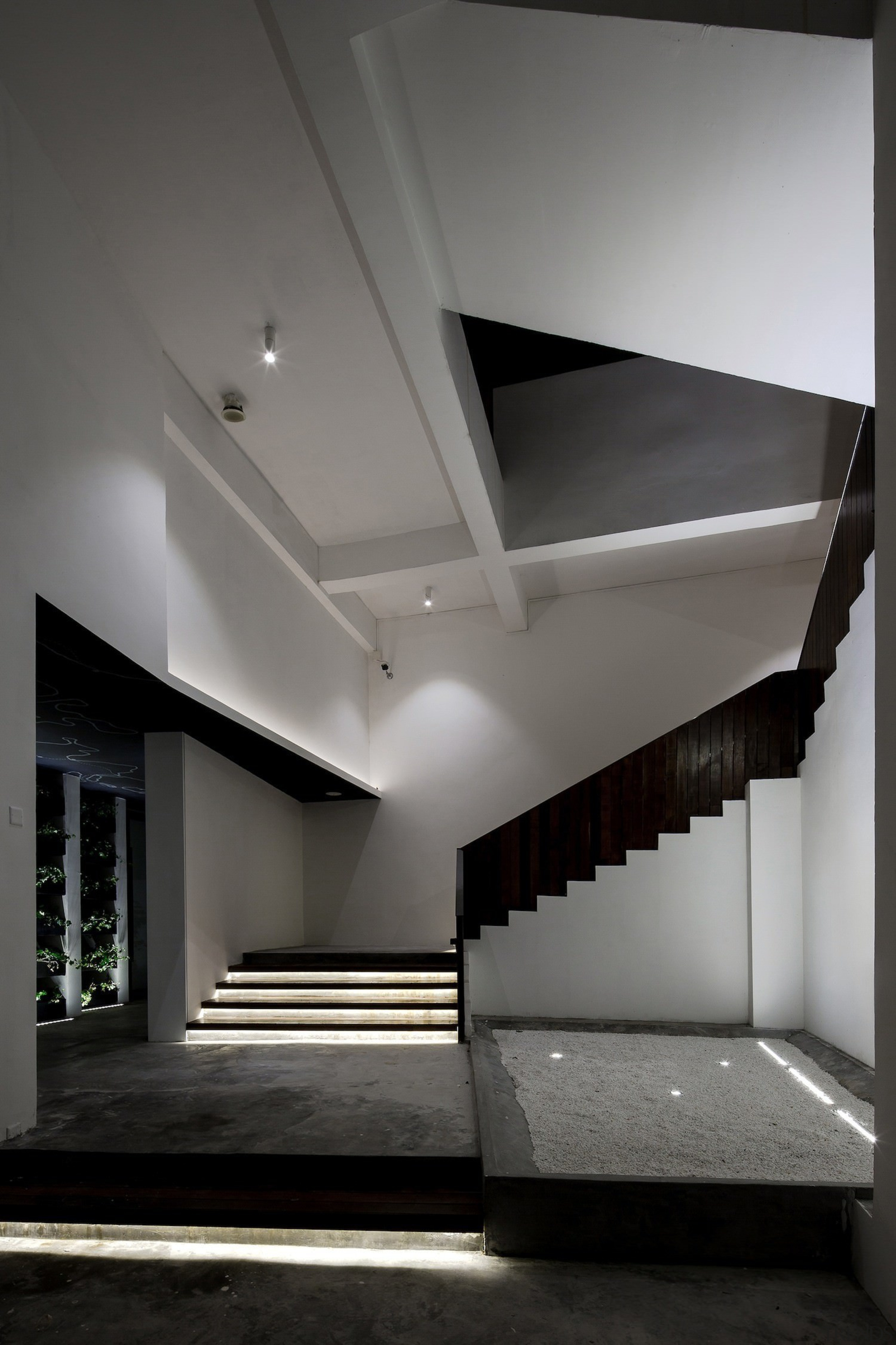 On the ground floor, you're guided by recessed architecture, black and white, ceiling, daylighting, house, interior design, light, monochrome, product design, gray, black
