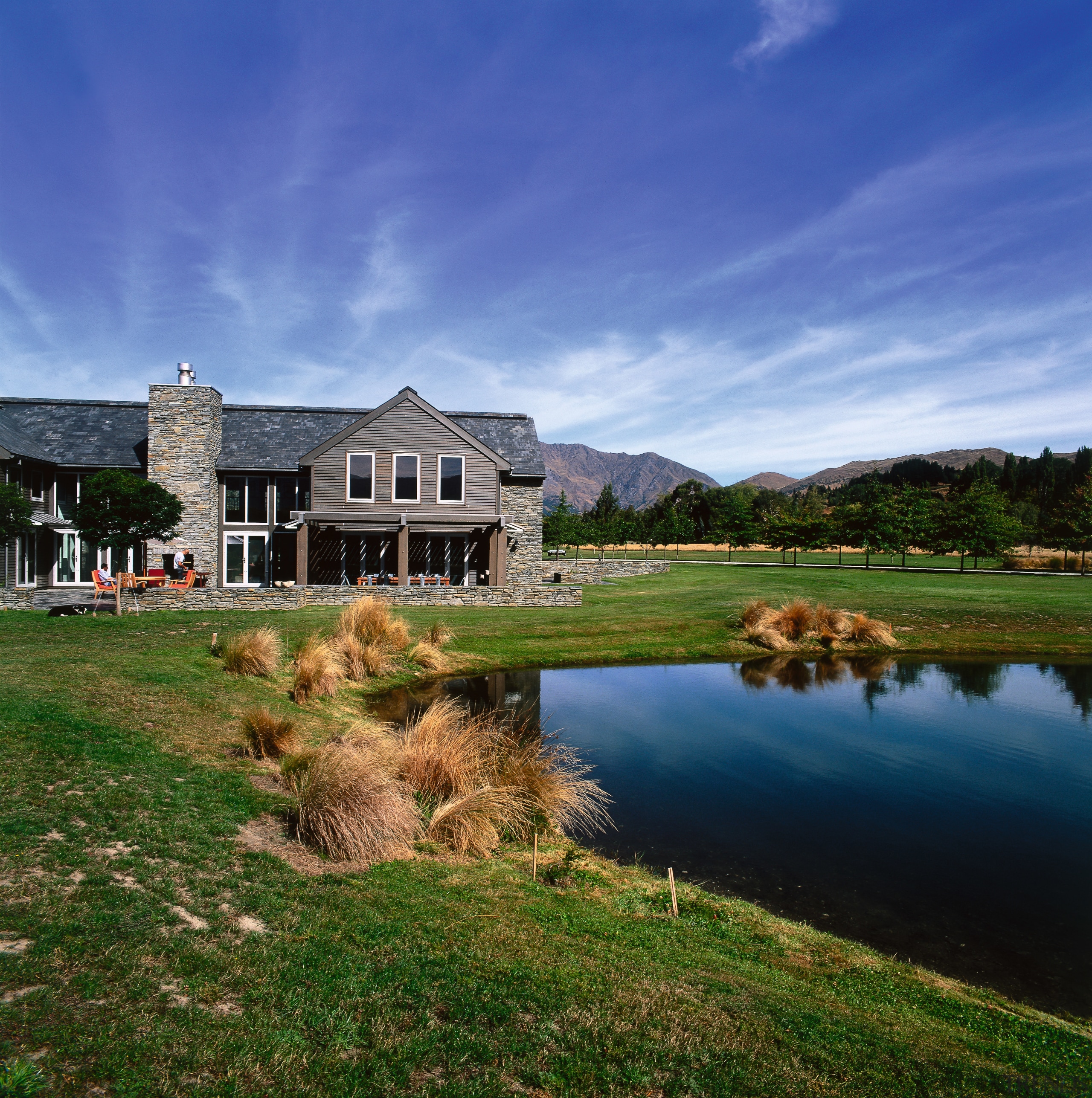 An exterior view of house with schist and cloud, cottage, estate, farm, farmhouse, field, grass, grassland, highland, home, house, lake, landscape, loch, meadow, national trust for places of historic interest or natural beauty, nature, pasture, property, real estate, reflection, rural area, sky, tree, water, blue, brown