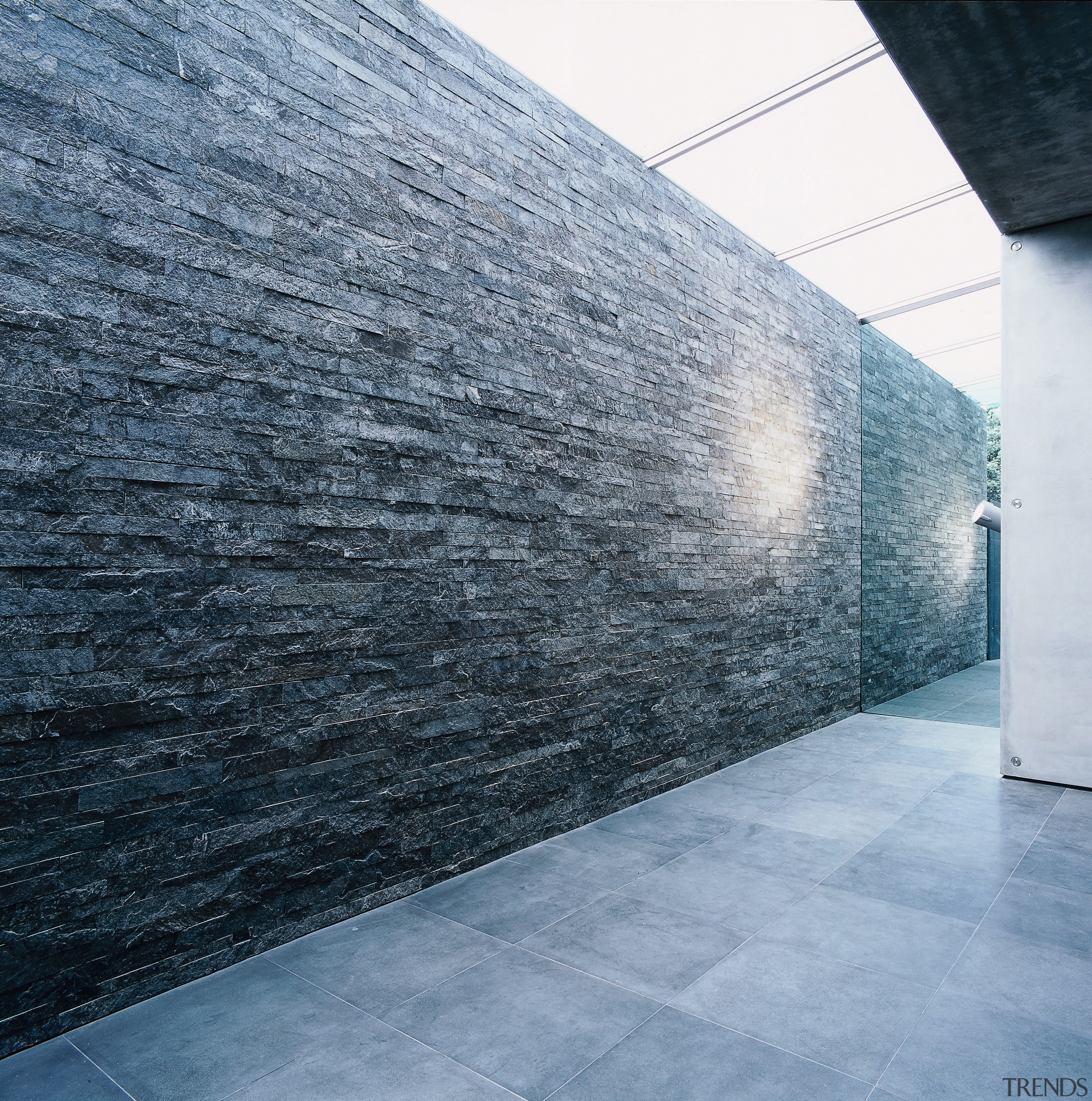 A view of a stone wall, grey tiled architecture, concrete, daylighting, floor, sky, wall, gray, black