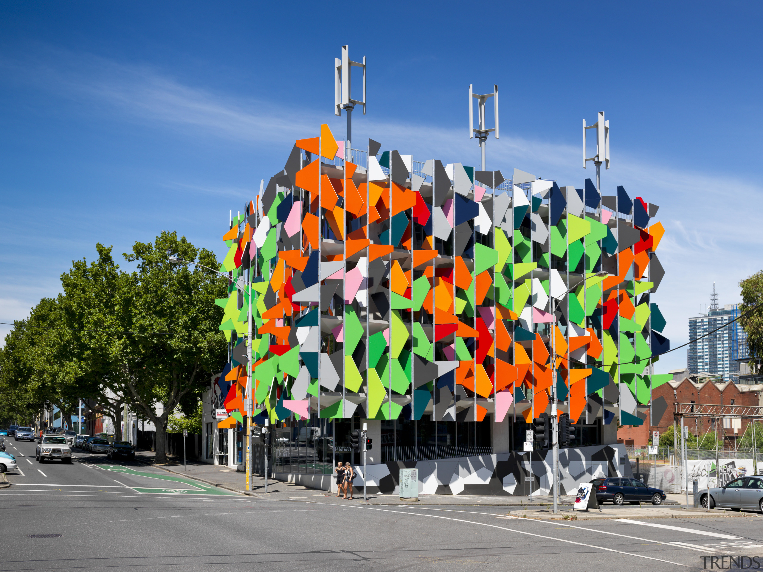 View of Pixel Building, with colorful exterior flags, mural, tree
