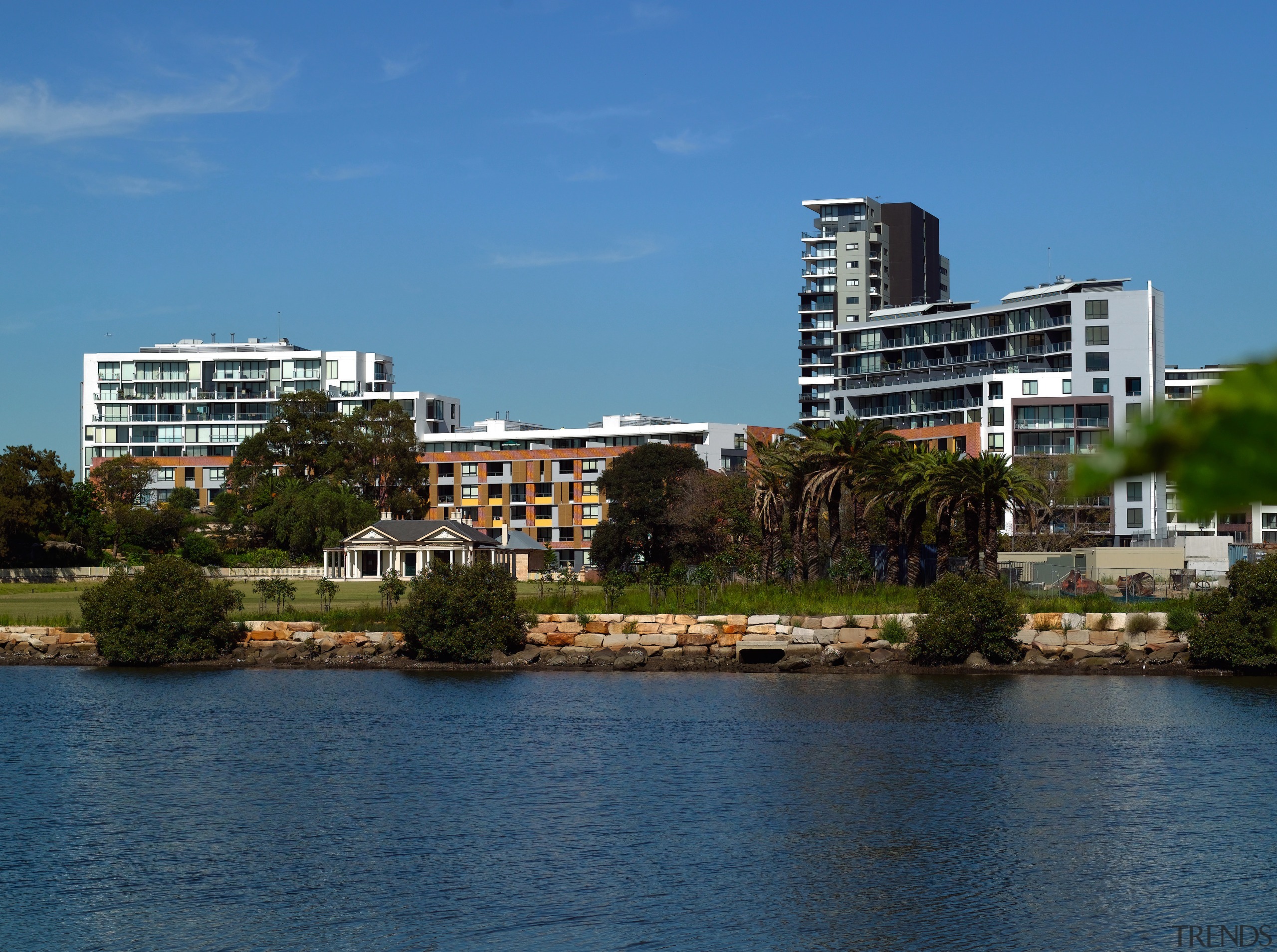 An exterior view of this multi storey apartment body of water, building, city, cityscape, condominium, daytime, downtown, home, lake, metropolitan area, real estate, reflection, residential area, river, sea, sky, skyline, suburb, tower block, tree, urban area, water, waterway, teal