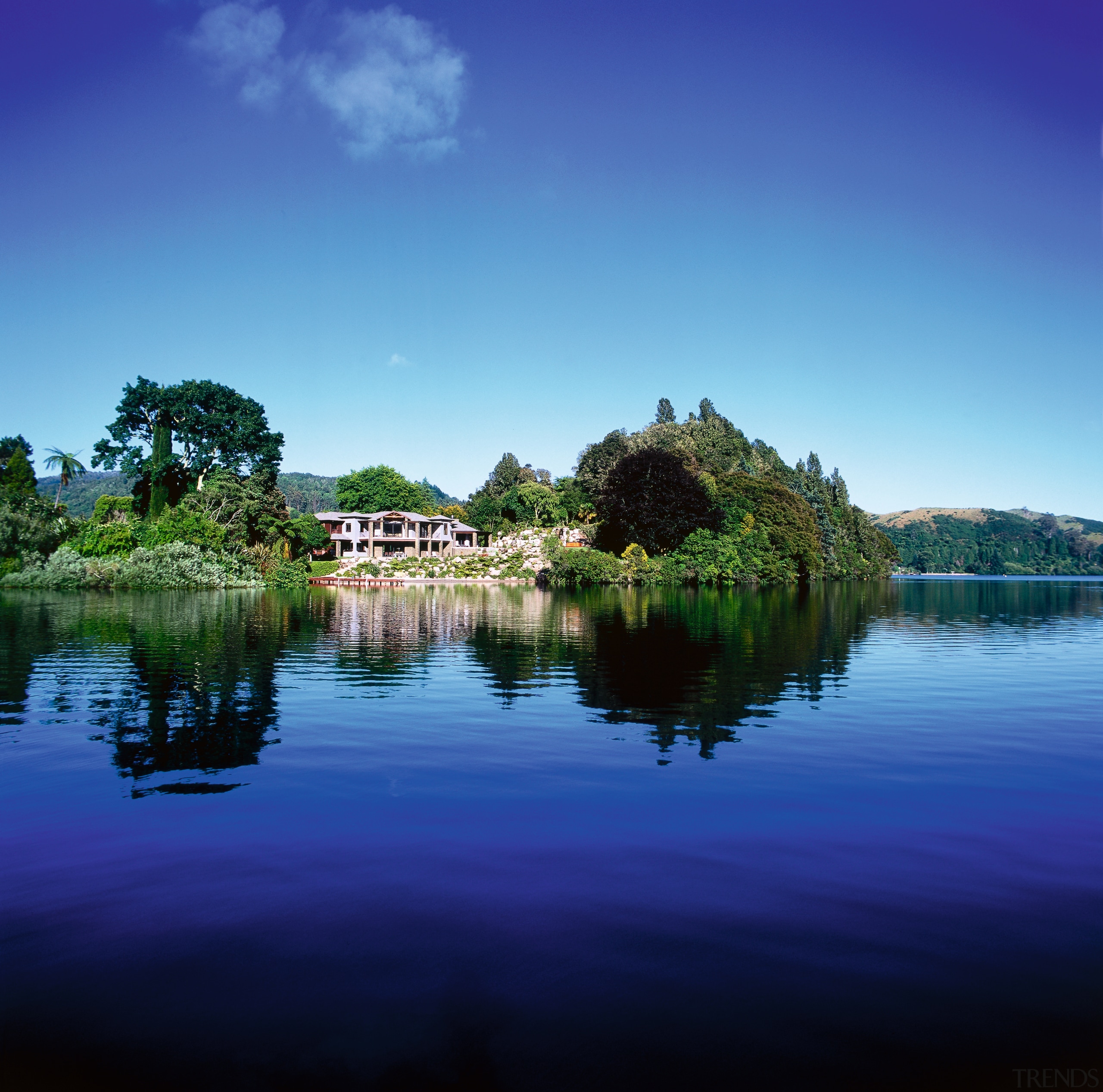 View of lakeside property. House is surrounded by atmosphere, bank, body of water, calm, cloud, daytime, grass, horizon, lake, landscape, loch, morning, nature, pond, reflection, reservoir, river, sky, tree, water, water resources, watercourse, waterway, wetland, blue, teal