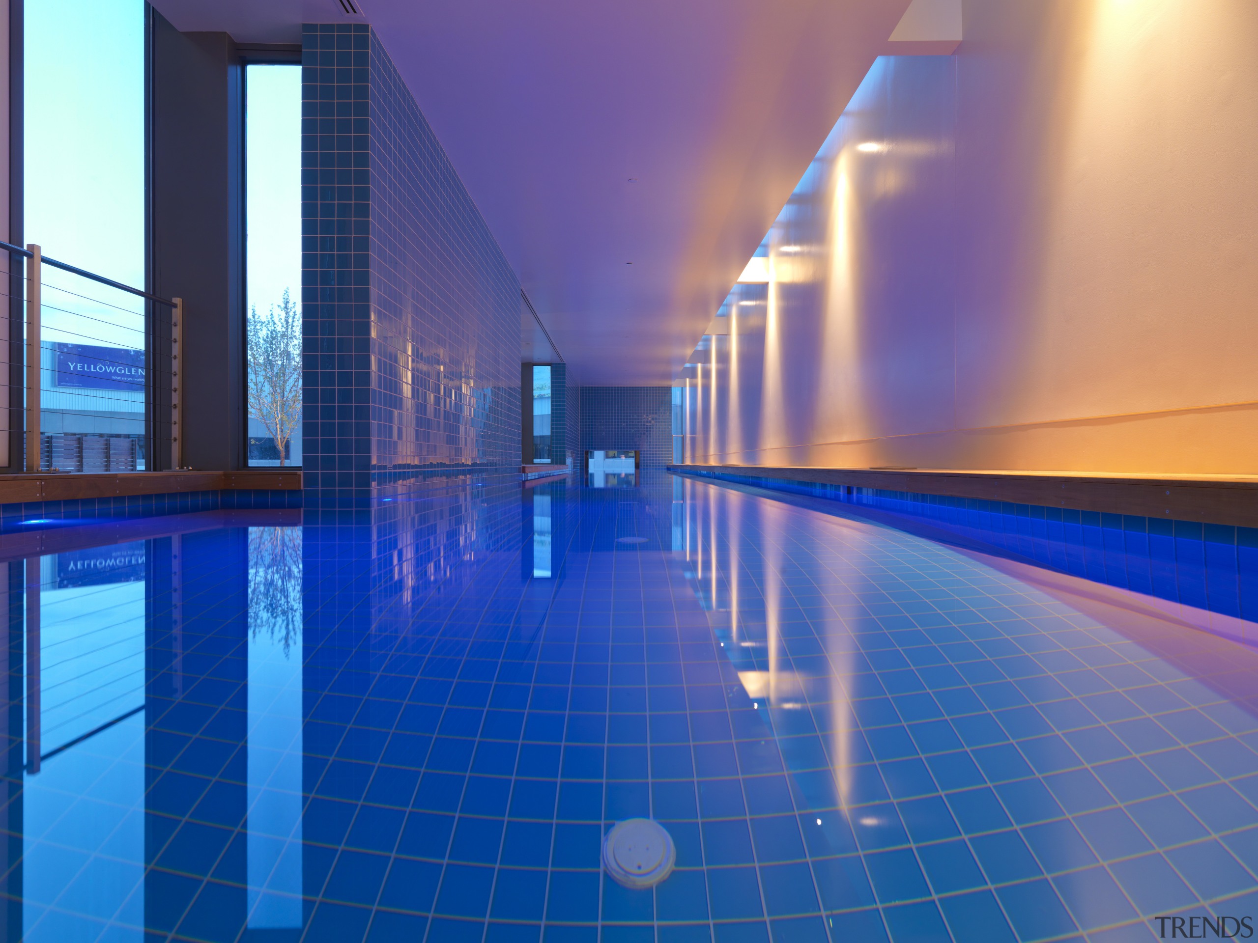 View of indoor cantilevered pool featuring wooden seating, architecture, blue, daylighting, leisure, leisure centre, light, lighting, reflection, swimming pool, blue