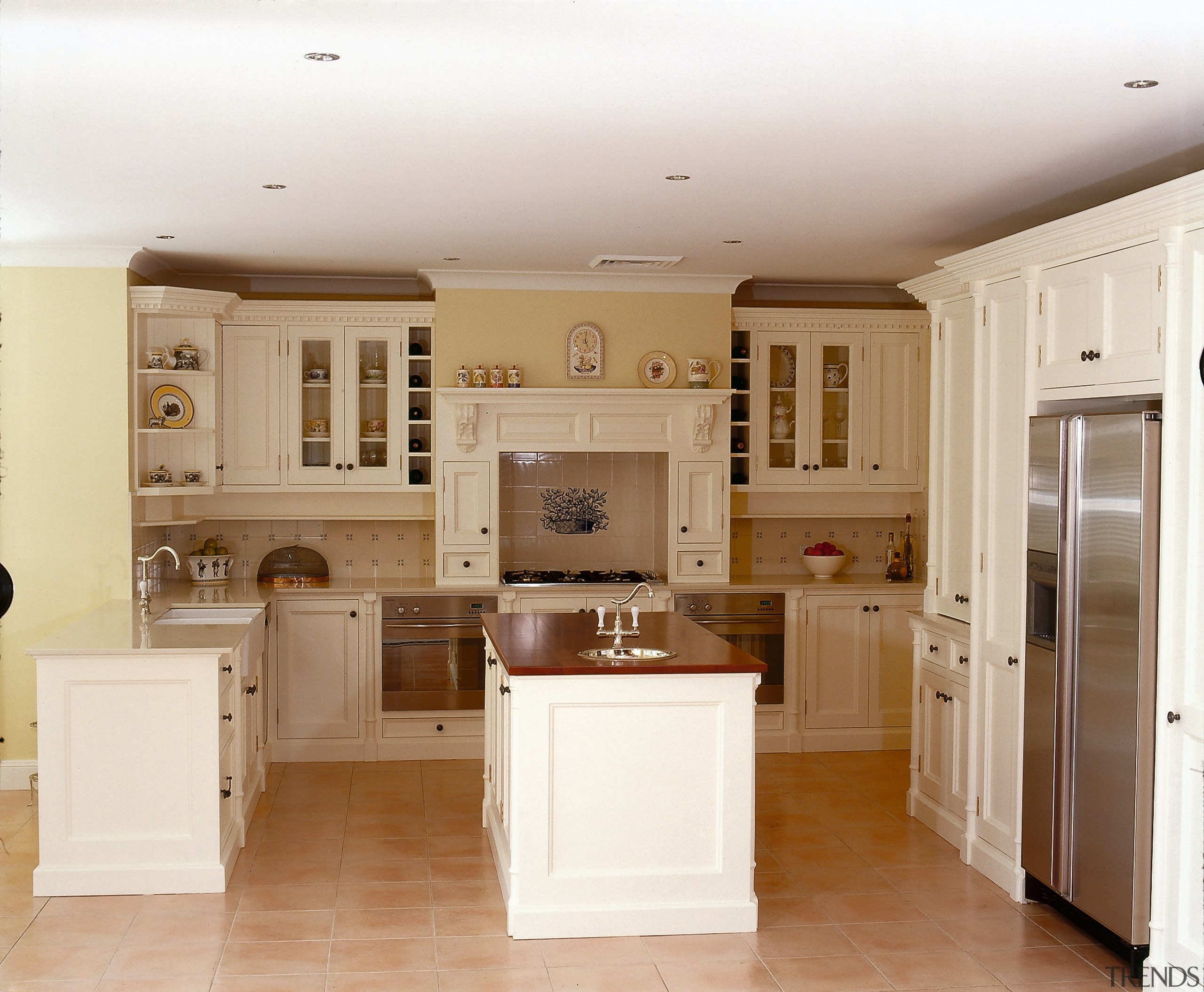 A classical styled kitchen featuring a  cooktop, cabinetry, ceiling, countertop, cuisine classique, floor, flooring, home, home appliance, interior design, kitchen, real estate, room, white, brown