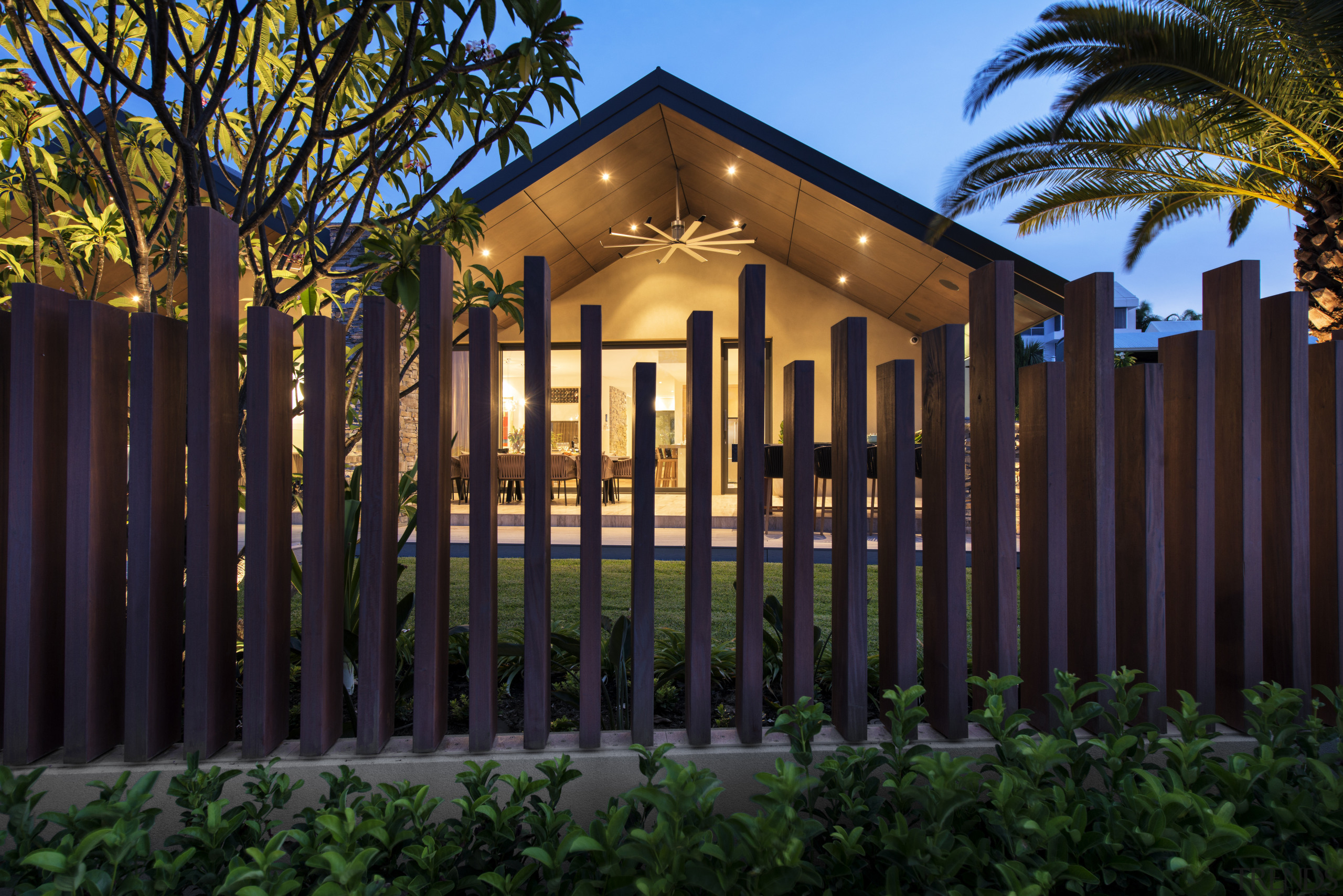 A palisade fences with irregular pickets separates the architecture, estate, facade, fence, grass, home, home fencing, house, landscape lighting, lighting, outdoor structure, property, real estate, residential area, black