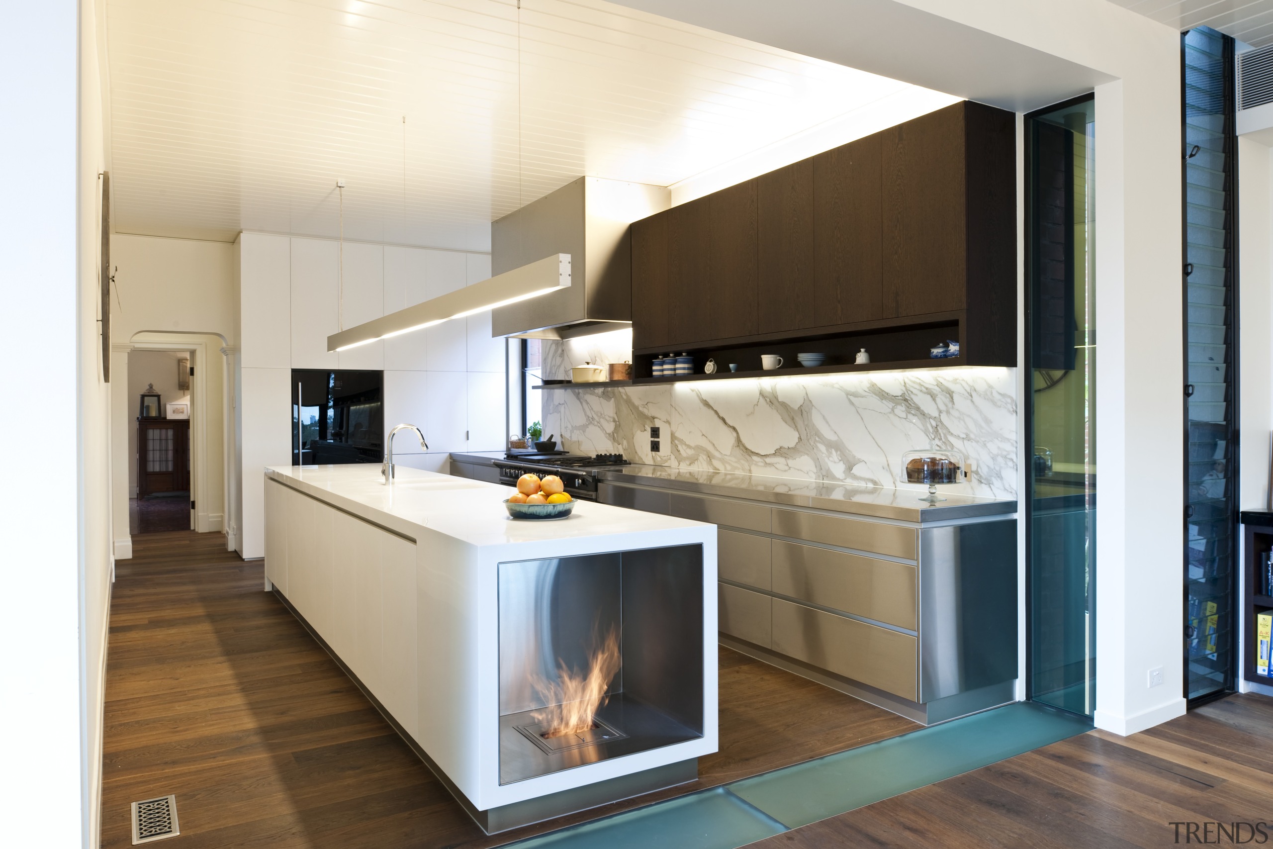 Fireplace built into island. Stainless steel appliances. Minimalistic cabinetry, countertop, cuisine classique, home appliance, interior design, kitchen, room, white