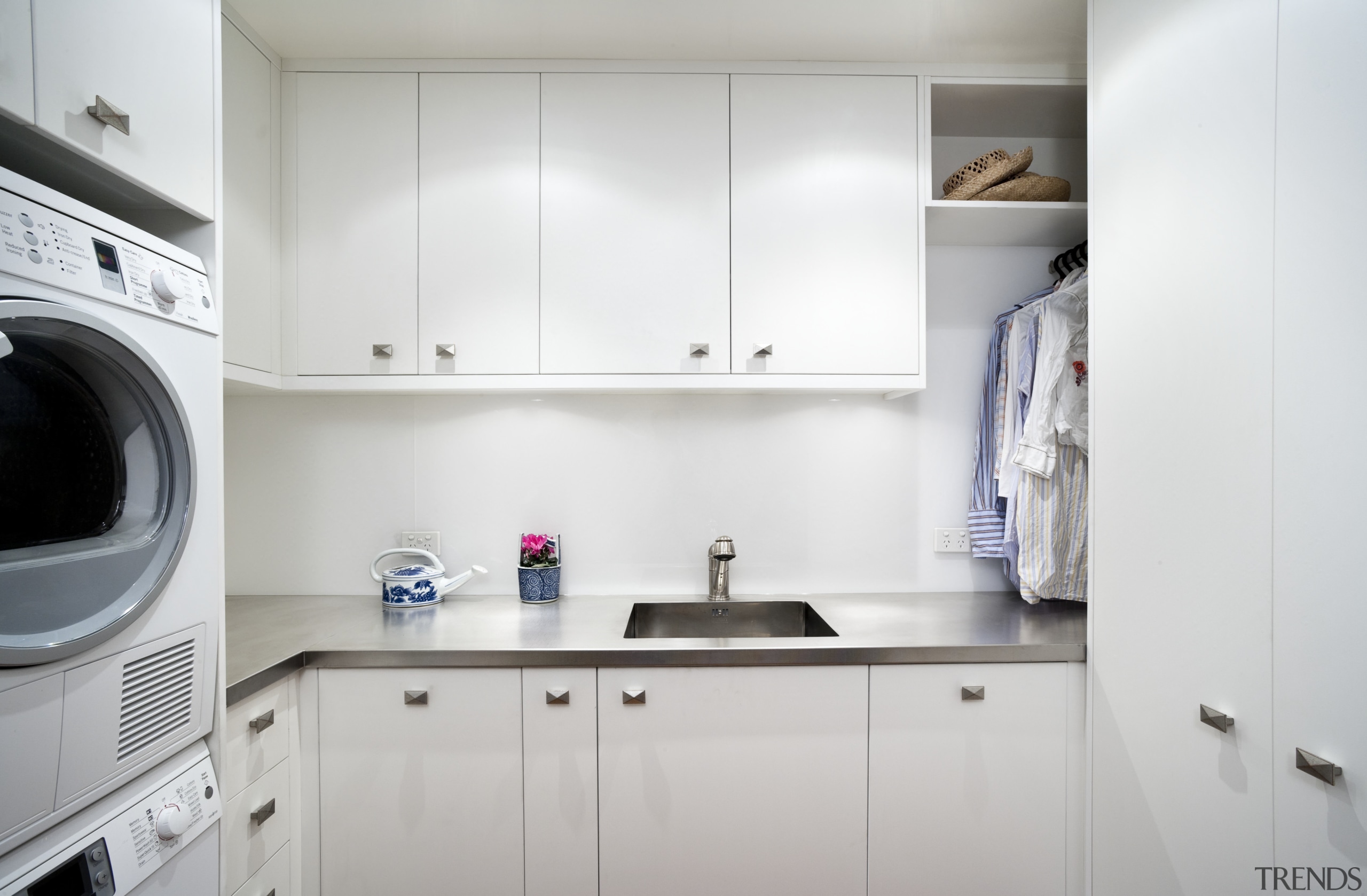 View of laundry which features white cabinetry, sink cabinetry, clothes dryer, countertop, home appliance, interior design, kitchen, laundry, laundry room, major appliance, product design, room, washing machine, gray, white