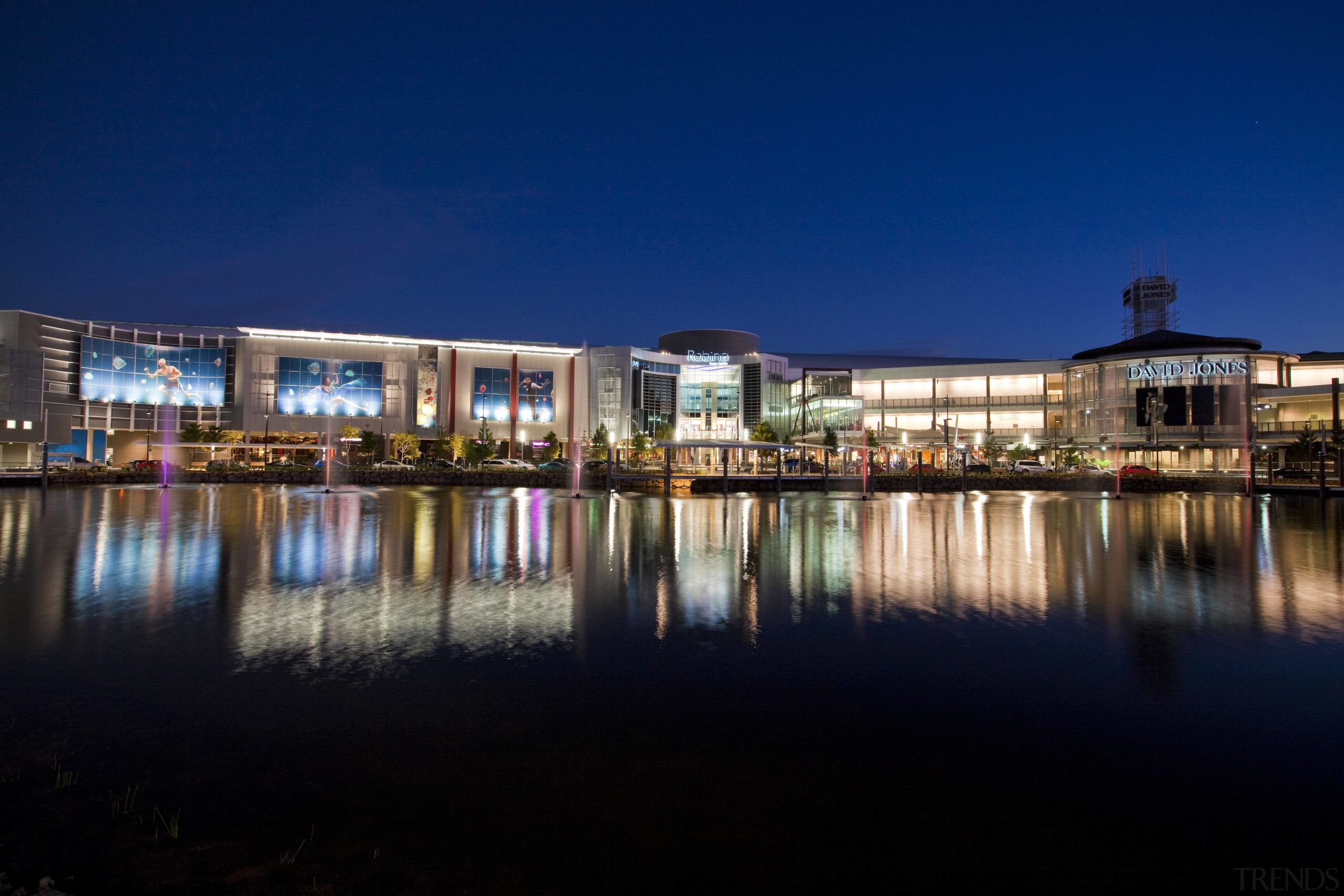 Exterior view of the Robina Town Centre where architecture, city, cityscape, dusk, estate, evening, home, hotel, lighting, mixed use, night, real estate, reflection, residential area, sky, tourist attraction, water, blue, black