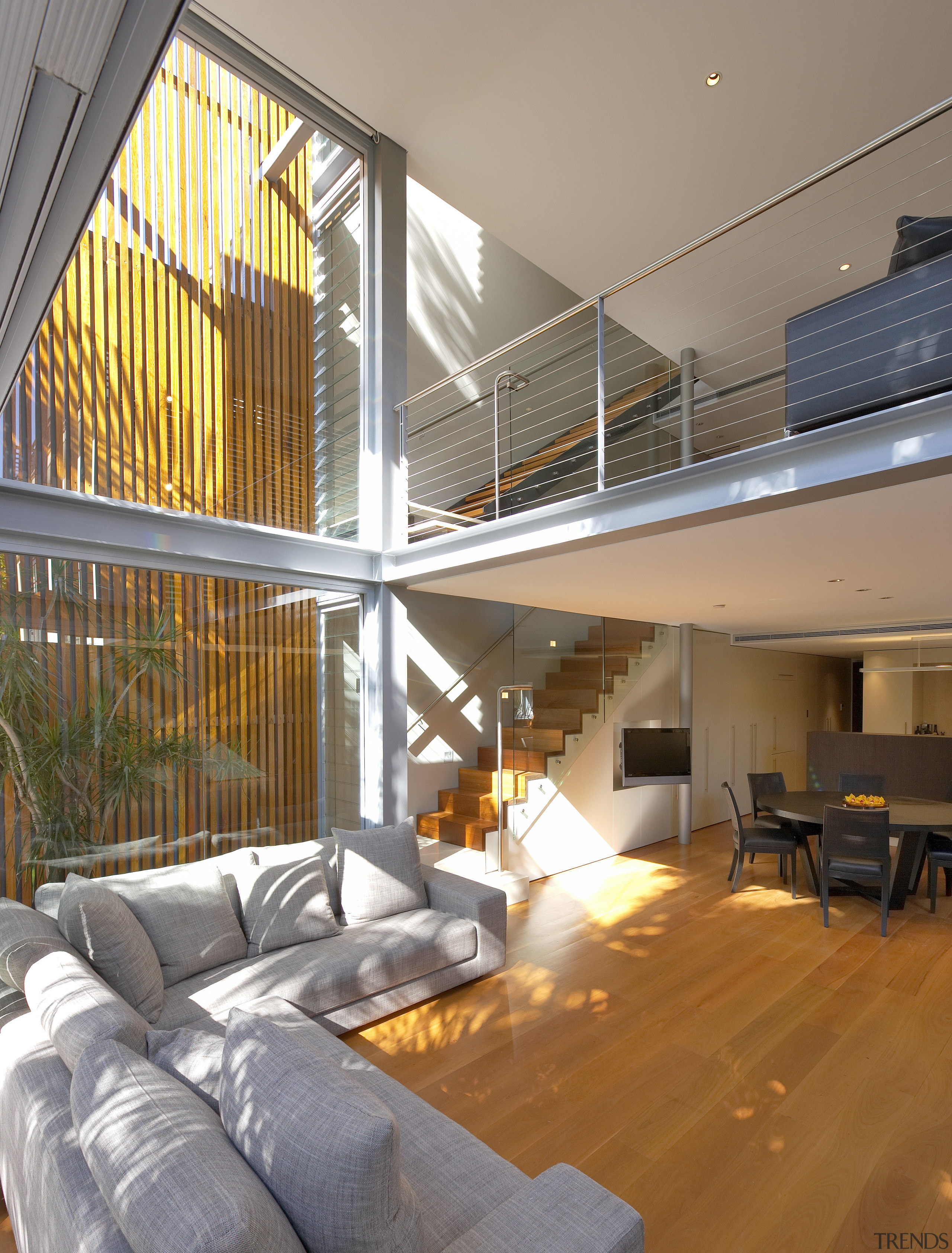 A glazed, three-storey atrium fills this home with apartment, architecture, ceiling, daylighting, estate, floor, handrail, home, house, interior design, living room, loft, penthouse apartment, real estate, stairs, window, wood, gray, brown