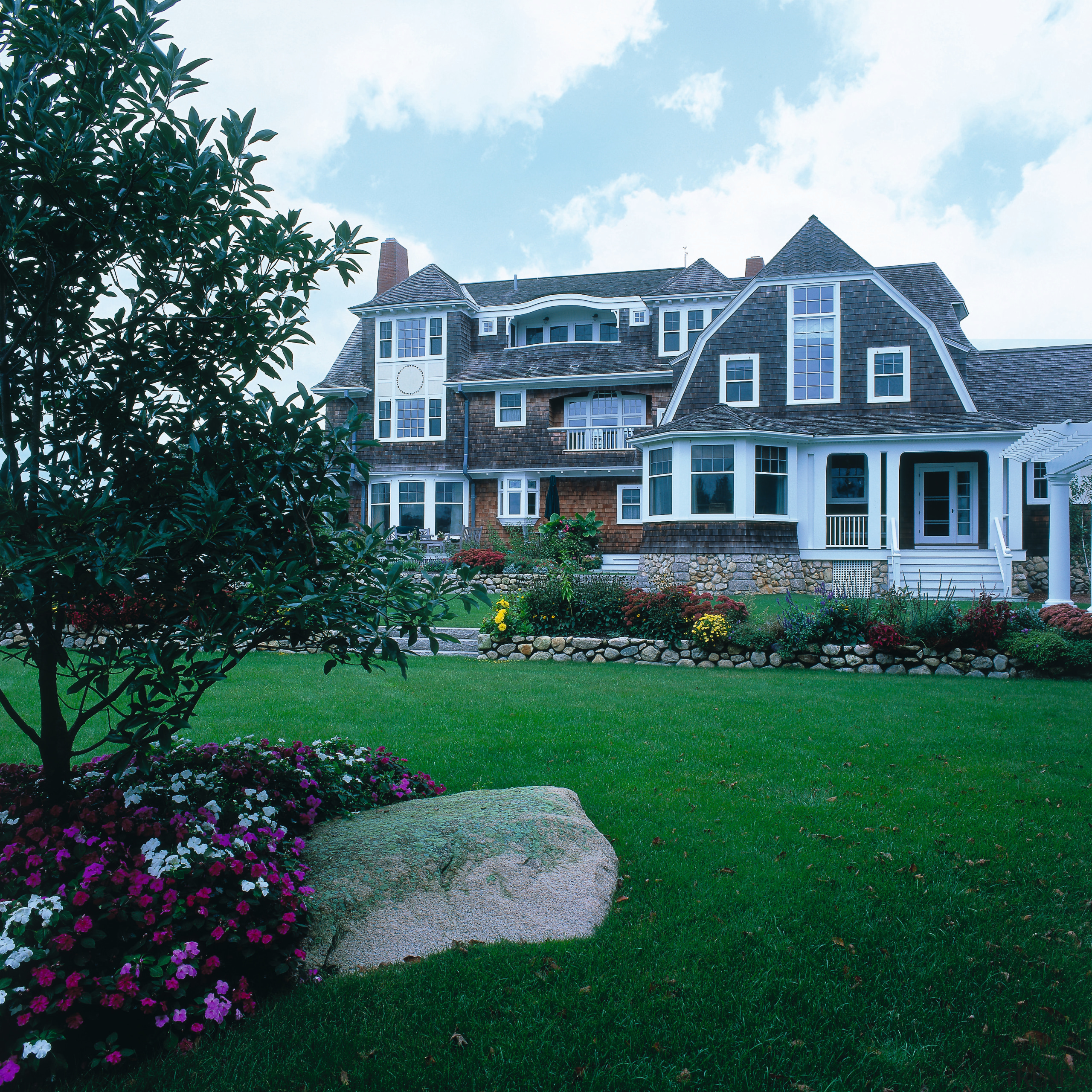 View of a wooden shingled vacation home, lawn, backyard, cottage, estate, facade, farmhouse, garden, grass, historic house, home, house, landscape, landscaping, lawn, mansion, neighbourhood, plant, property, real estate, residential area, siding, suburb, tree, yard, teal