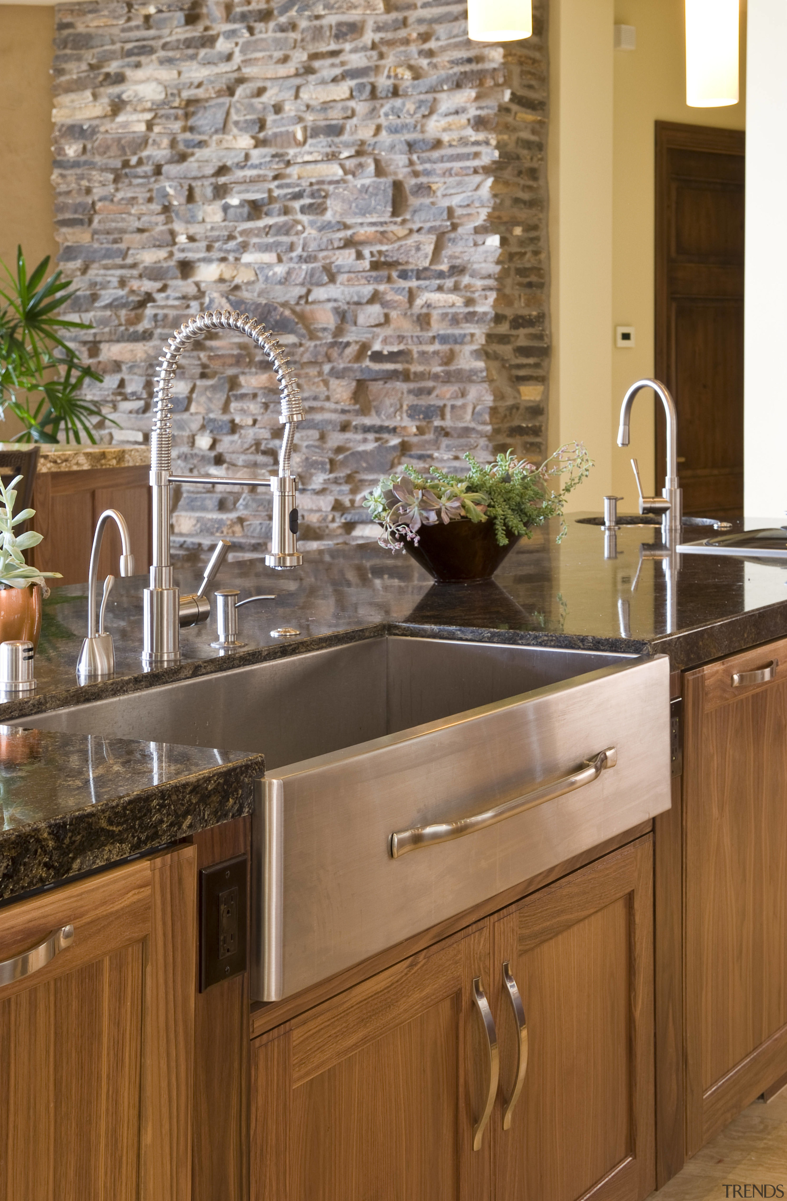 View of the kitchen which features a custom cabinetry, countertop, floor, flooring, hardwood, home, interior design, kitchen, room, sink, tile, wall, brown