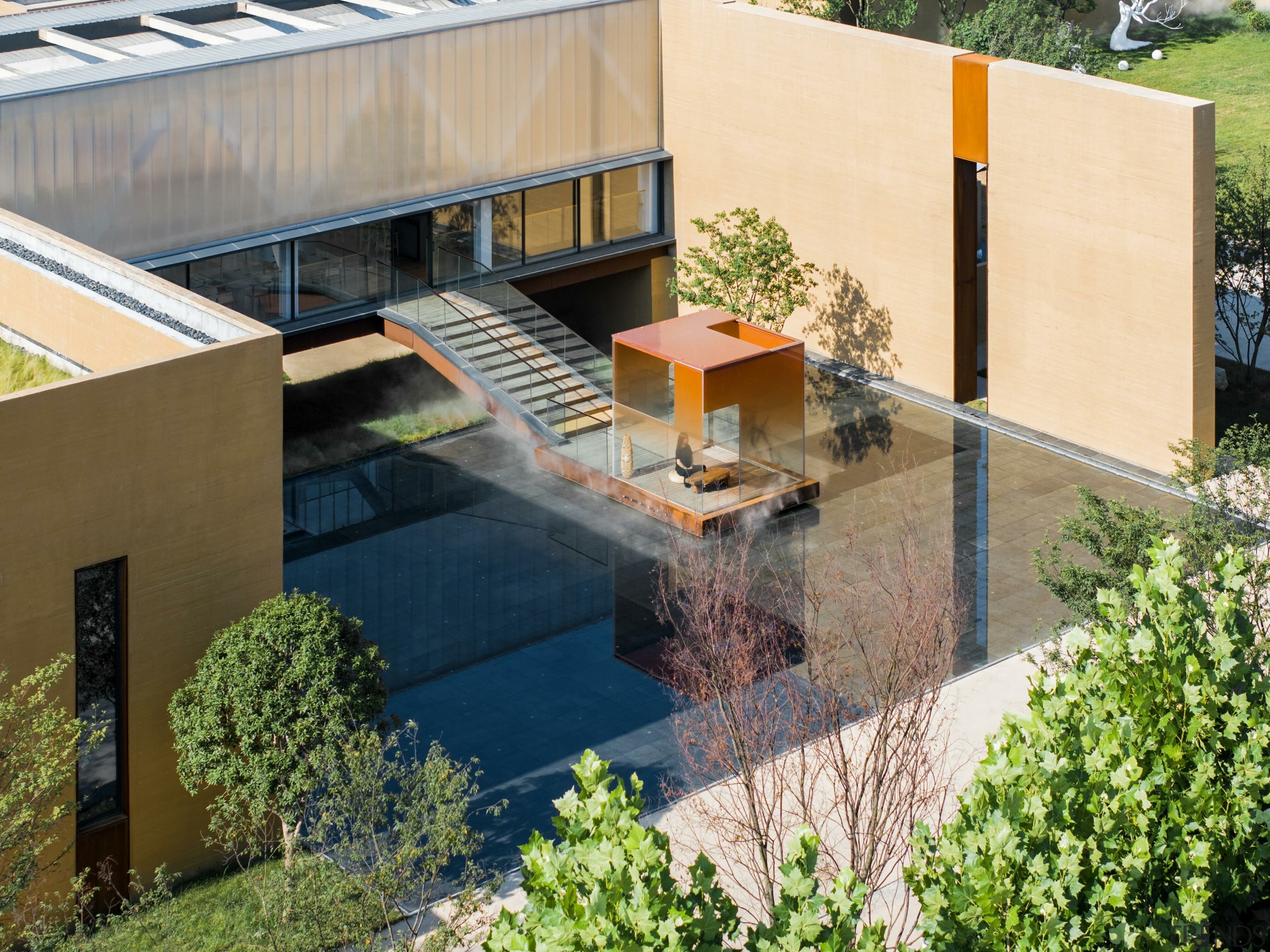 A Zen-inspired orange glass pavilion set over water, 