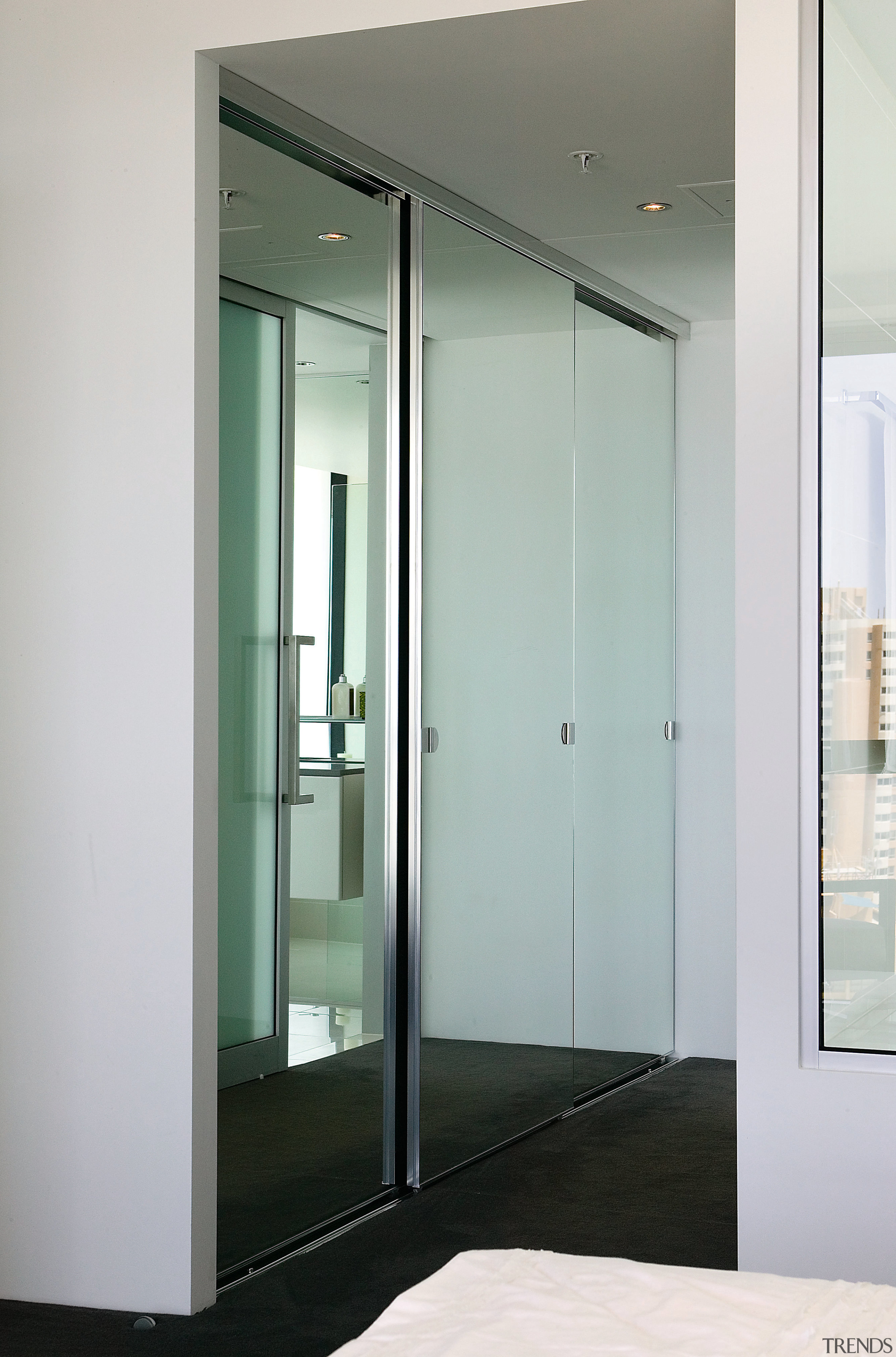 A view of the bedrrom featuring frameless mirrored door, glass, gray