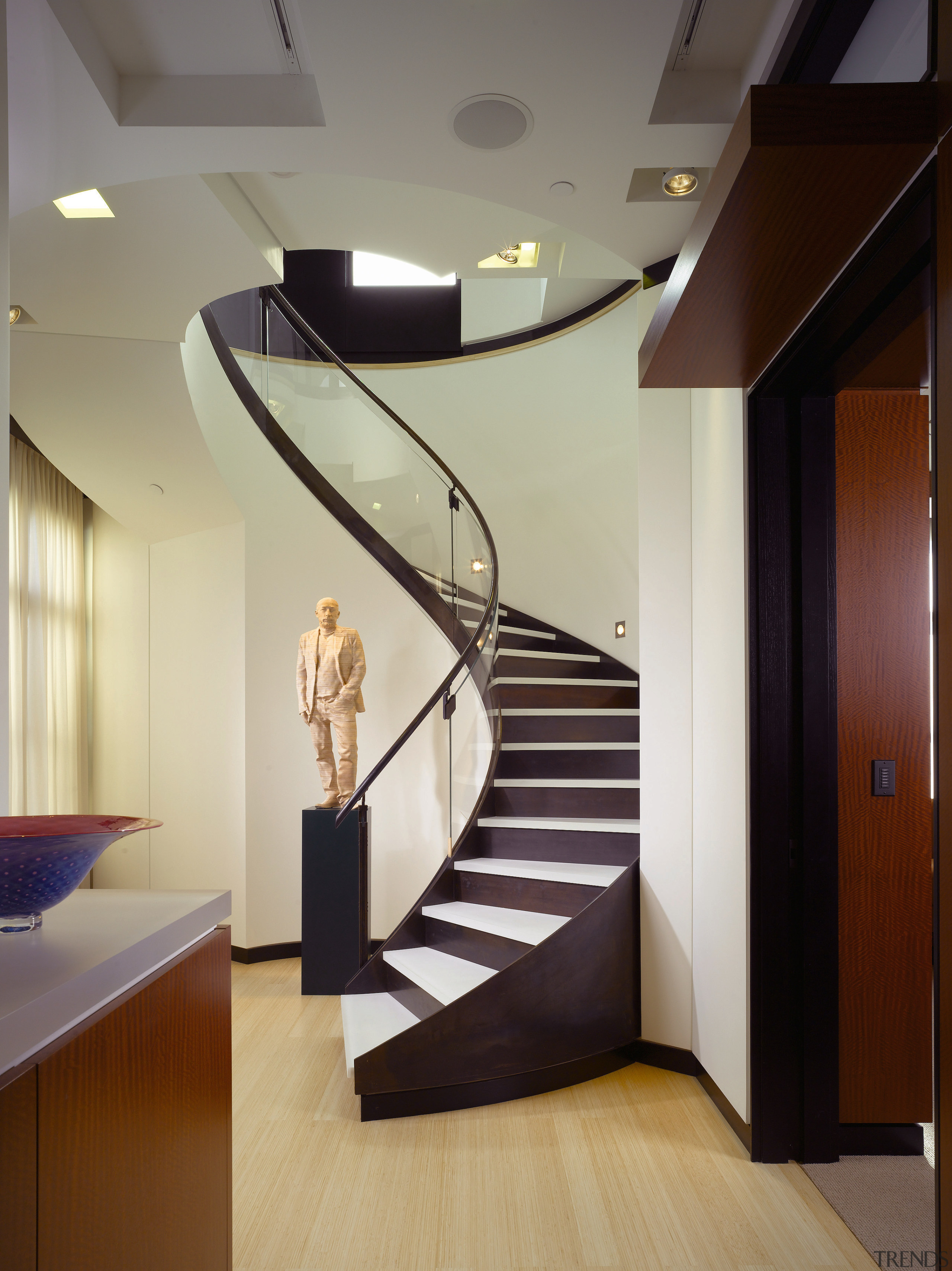 view of stairway featuring spiral staircase, wooden floors, architecture, ceiling, daylighting, floor, flooring, handrail, hardwood, interior design, lighting, lobby, stairs, gray