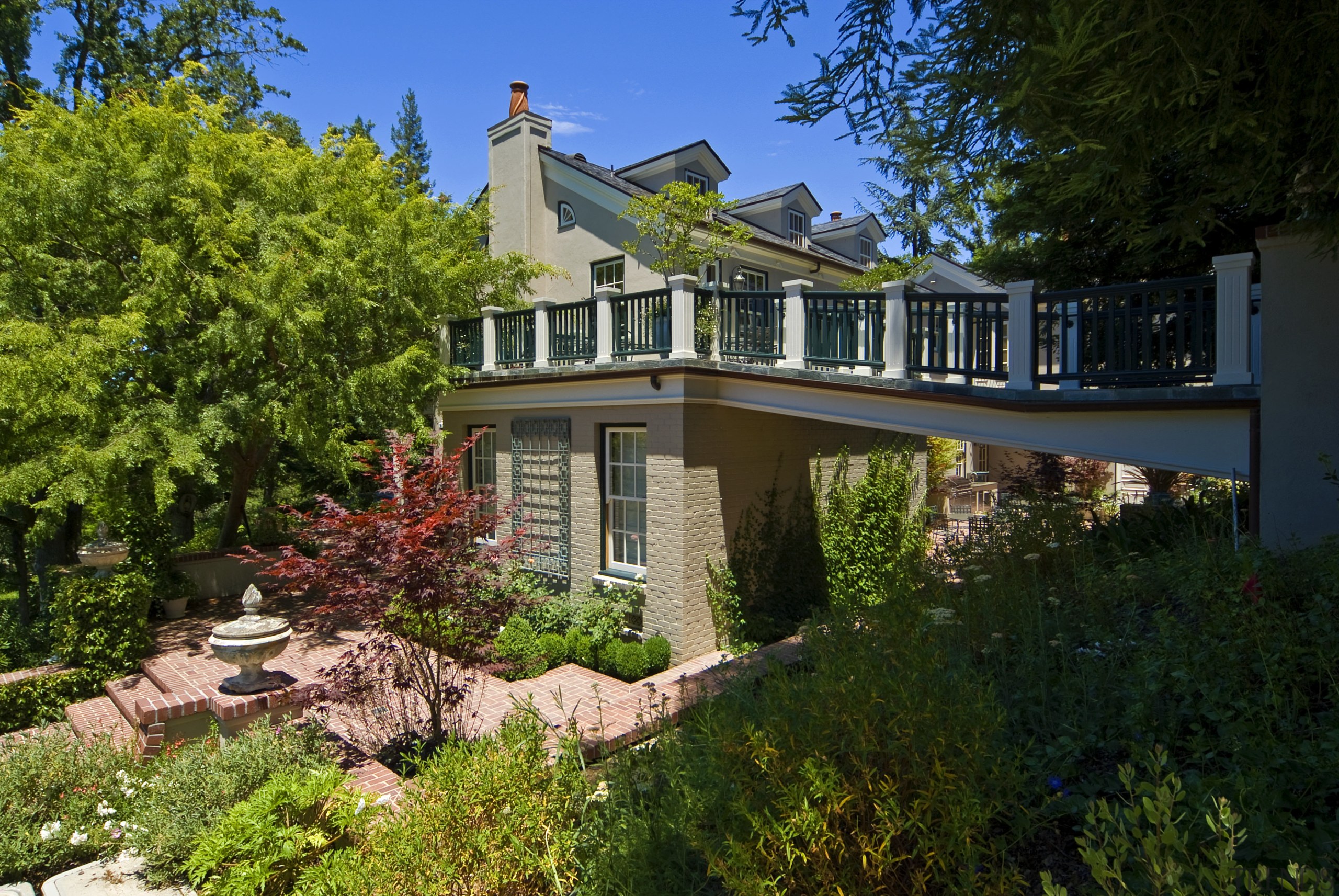 View of walkway to home with garden area. cottage, estate, facade, home, house, landscaping, mansion, outdoor structure, plant, property, real estate, residential area, sky, tree, villa, brown, black