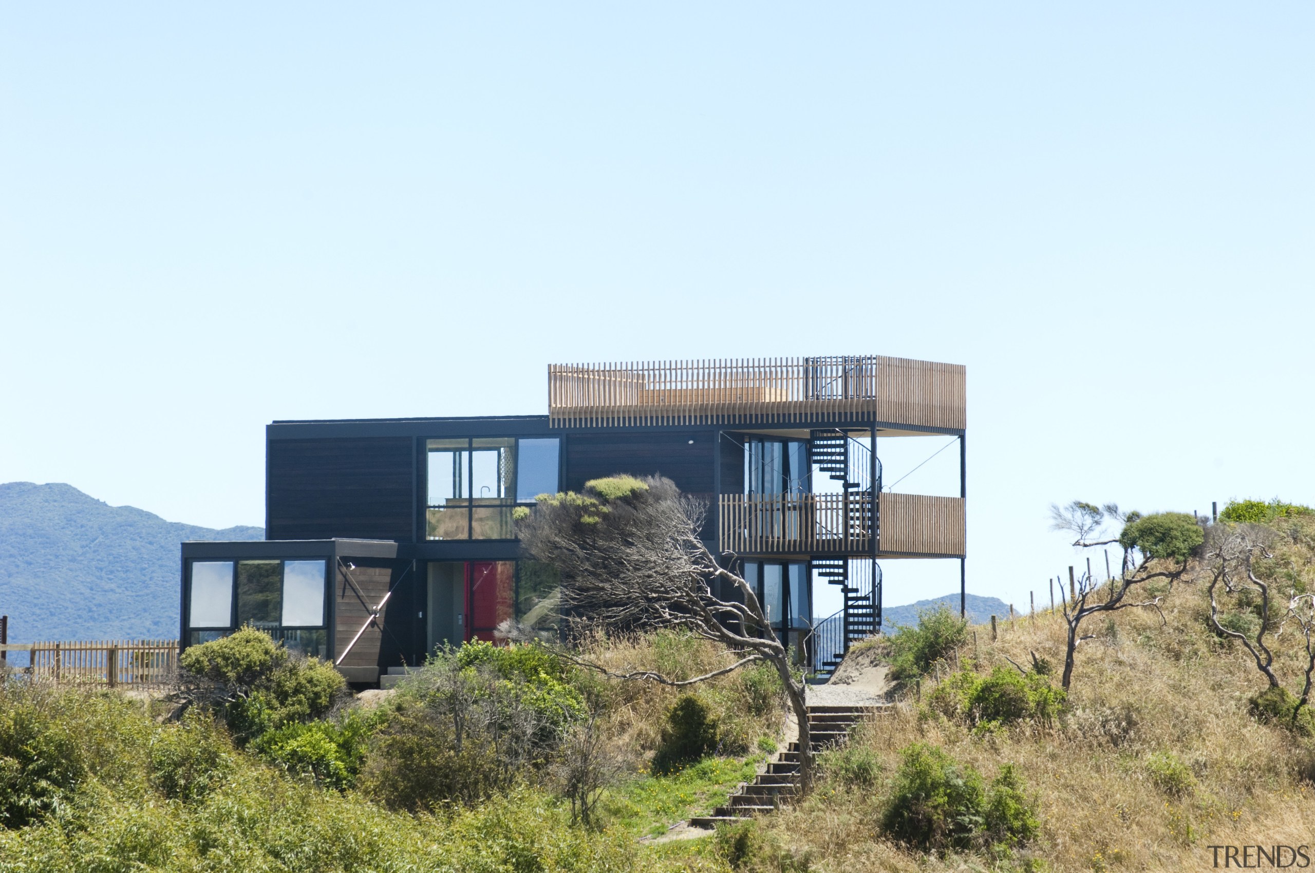 View of contemporary multi-level home with tussock landscape. architecture, building, home, house, property, real estate, sky, white