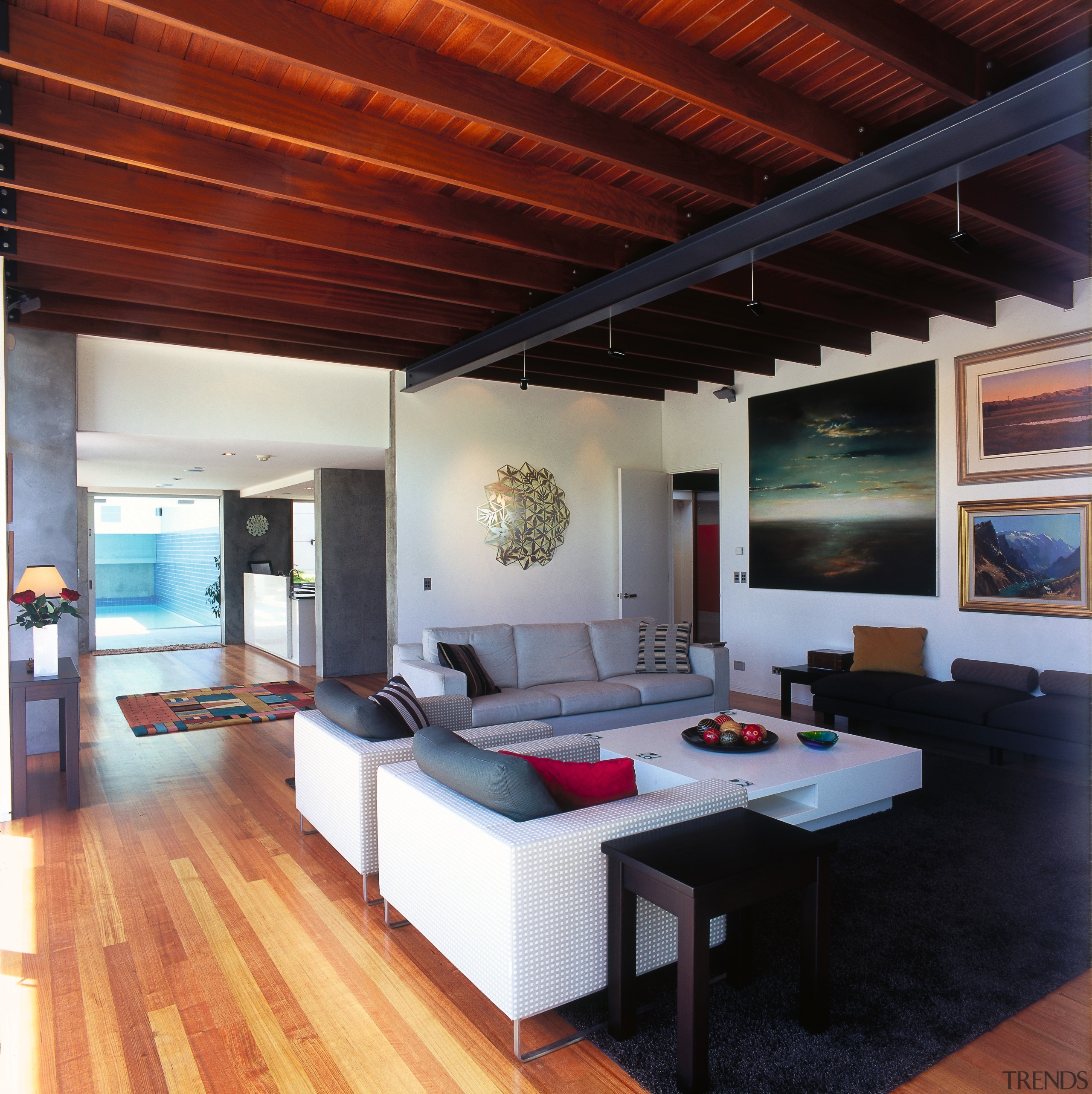 A view of the living area featuring white ceiling, floor, flooring, hardwood, house, interior design, living room, loft, real estate, room, table, wood, wood flooring, red