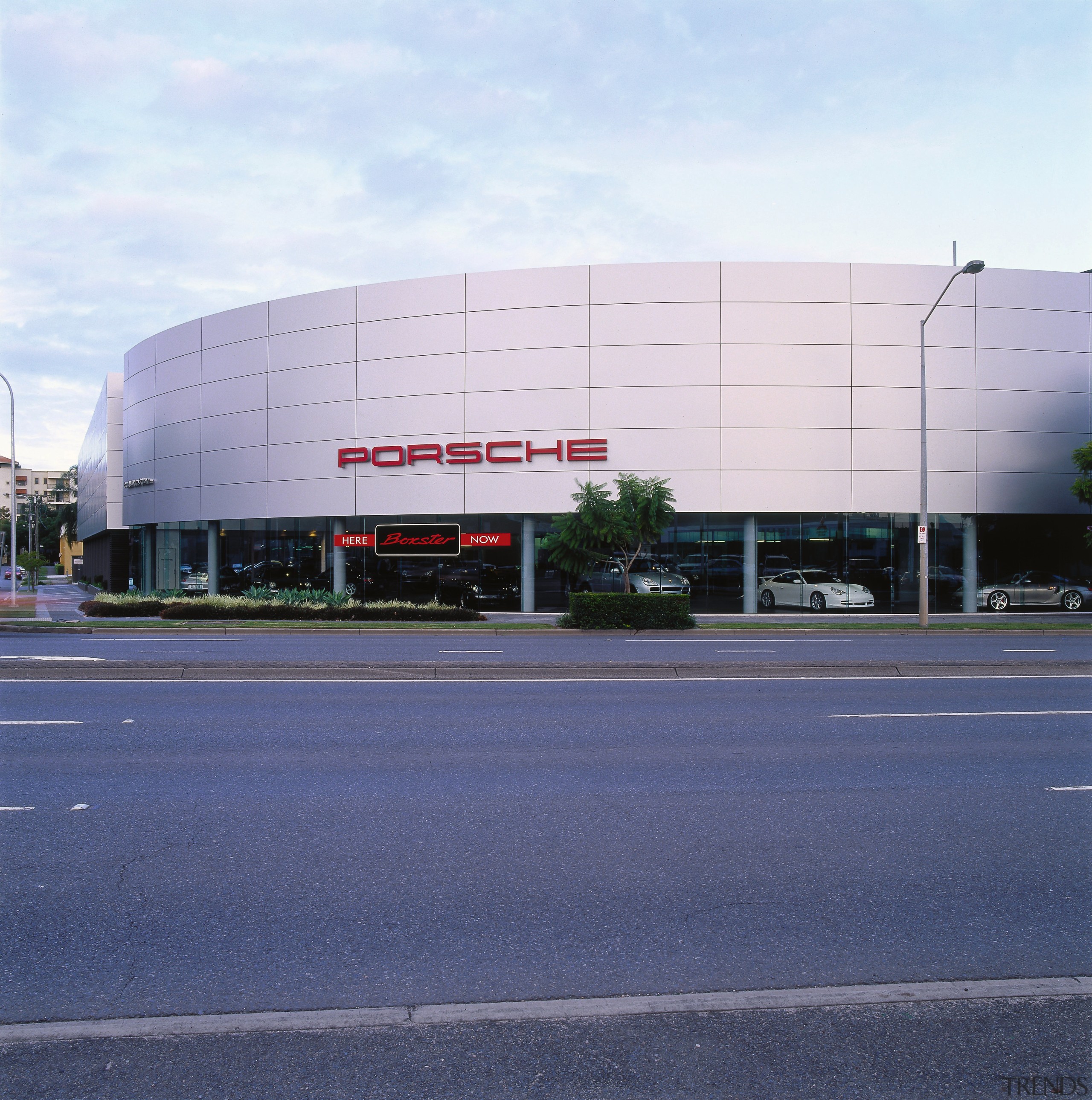 view of the porsche building will glazing and architecture, asphalt, building, commercial building, corporate headquarters, daytime, facade, headquarters, infrastructure, metropolitan area, sky, structure, white, blue