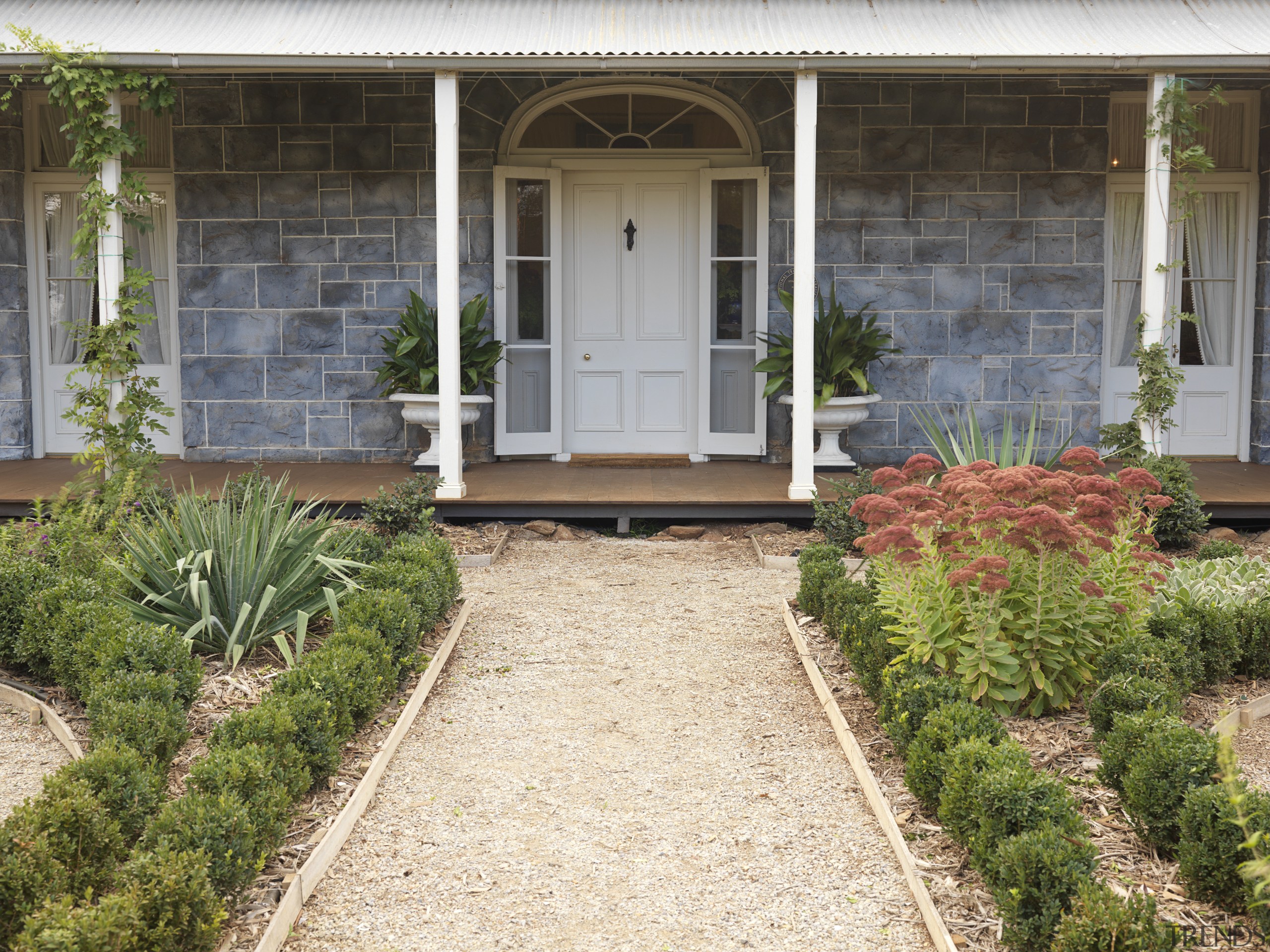 Exterior view of a colonial-styled architectural home with backyard, courtyard, estate, garden, grass, home, house, landscaping, outdoor structure, plant, porch, real estate, walkway, window, yard, brown