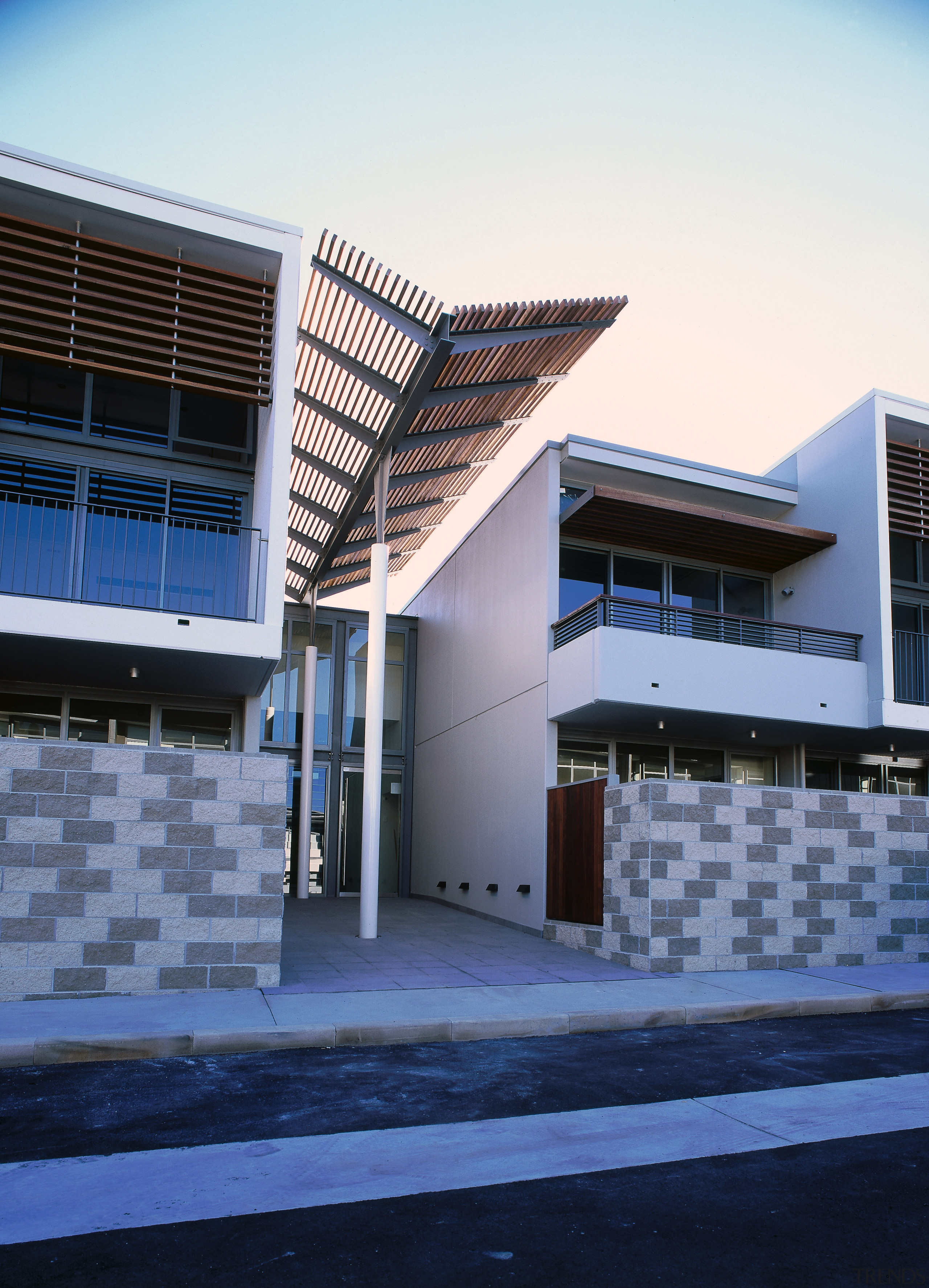 An exterior view of an entrance way with architecture, building, commercial building, condominium, corporate headquarters, daylighting, daytime, facade, headquarters, house, property, real estate, residential area, sky, window, blue, white