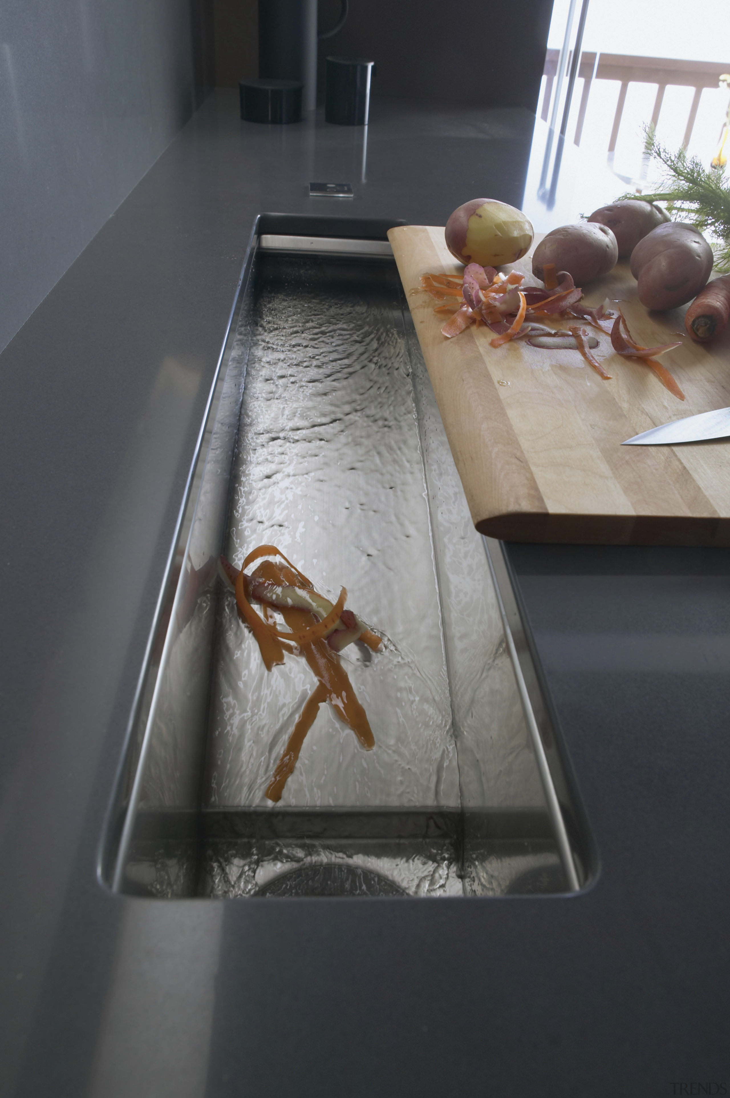 Image of Kohler's trough-like Crevasse rinsing sink where floor, flooring, table, wood, black, gray