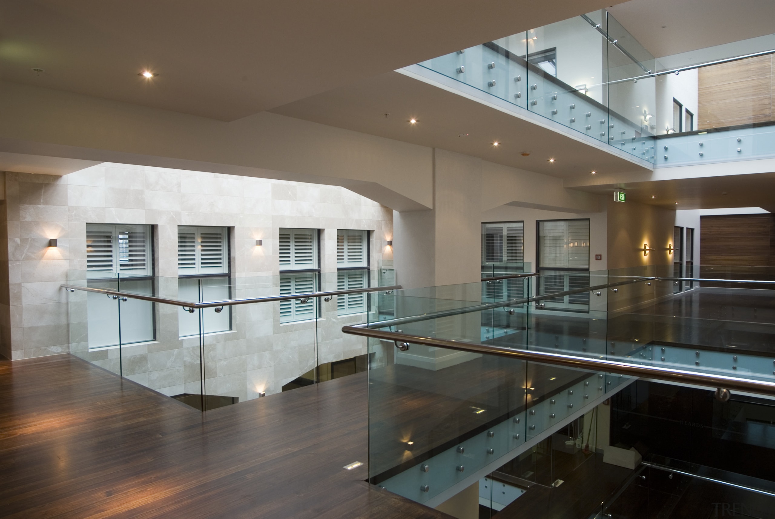 The solidity of the heards building ois expressed apartment, architecture, ceiling, condominium, daylighting, estate, floor, flooring, glass, handrail, hardwood, house, interior design, lobby, property, real estate, brown, gray