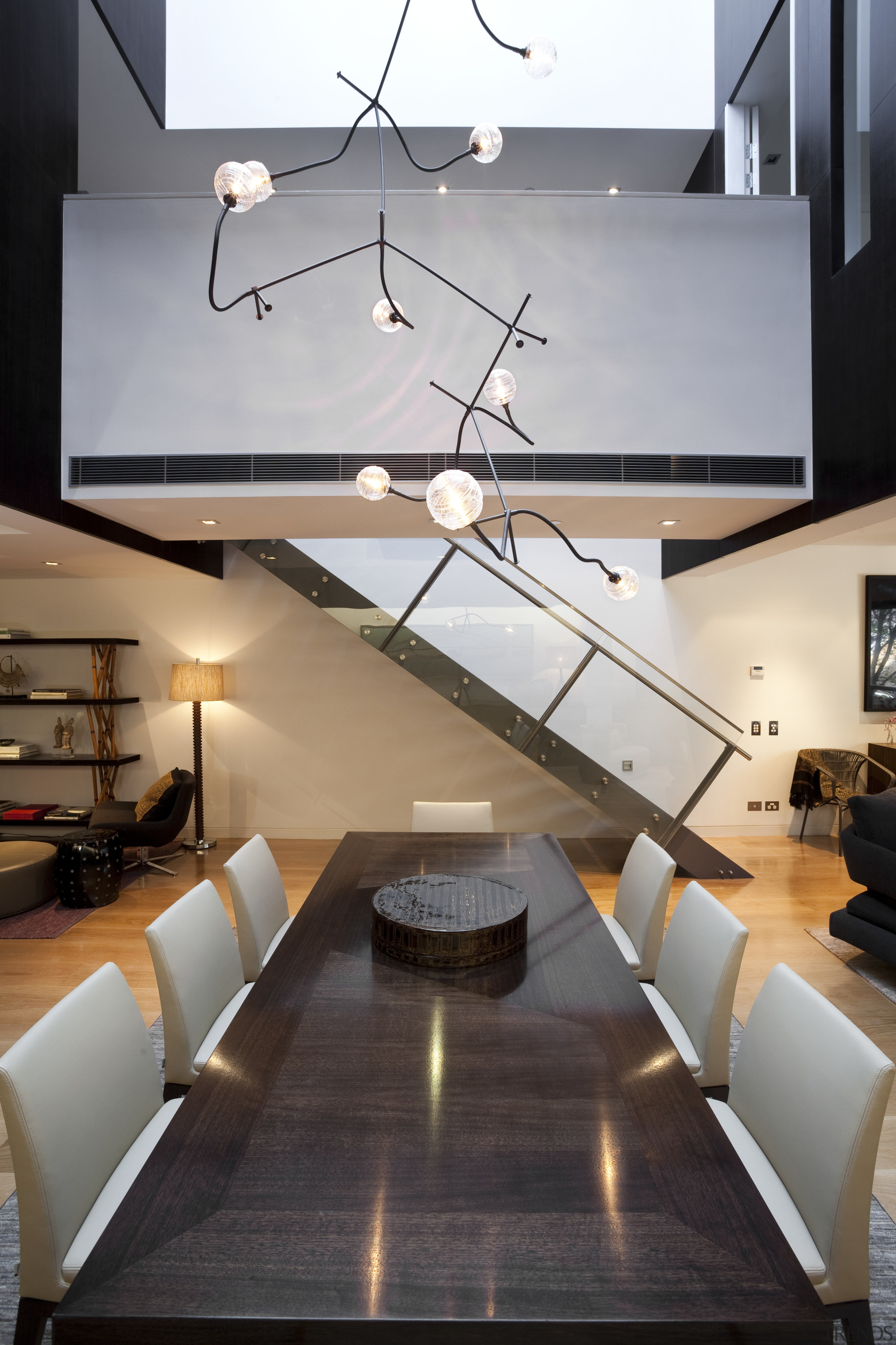 View of dining area in contemporary apartment. - architecture, ceiling, floor, home, interior design, light fixture, lighting, living room, loft, product design, table, wall, gray, black