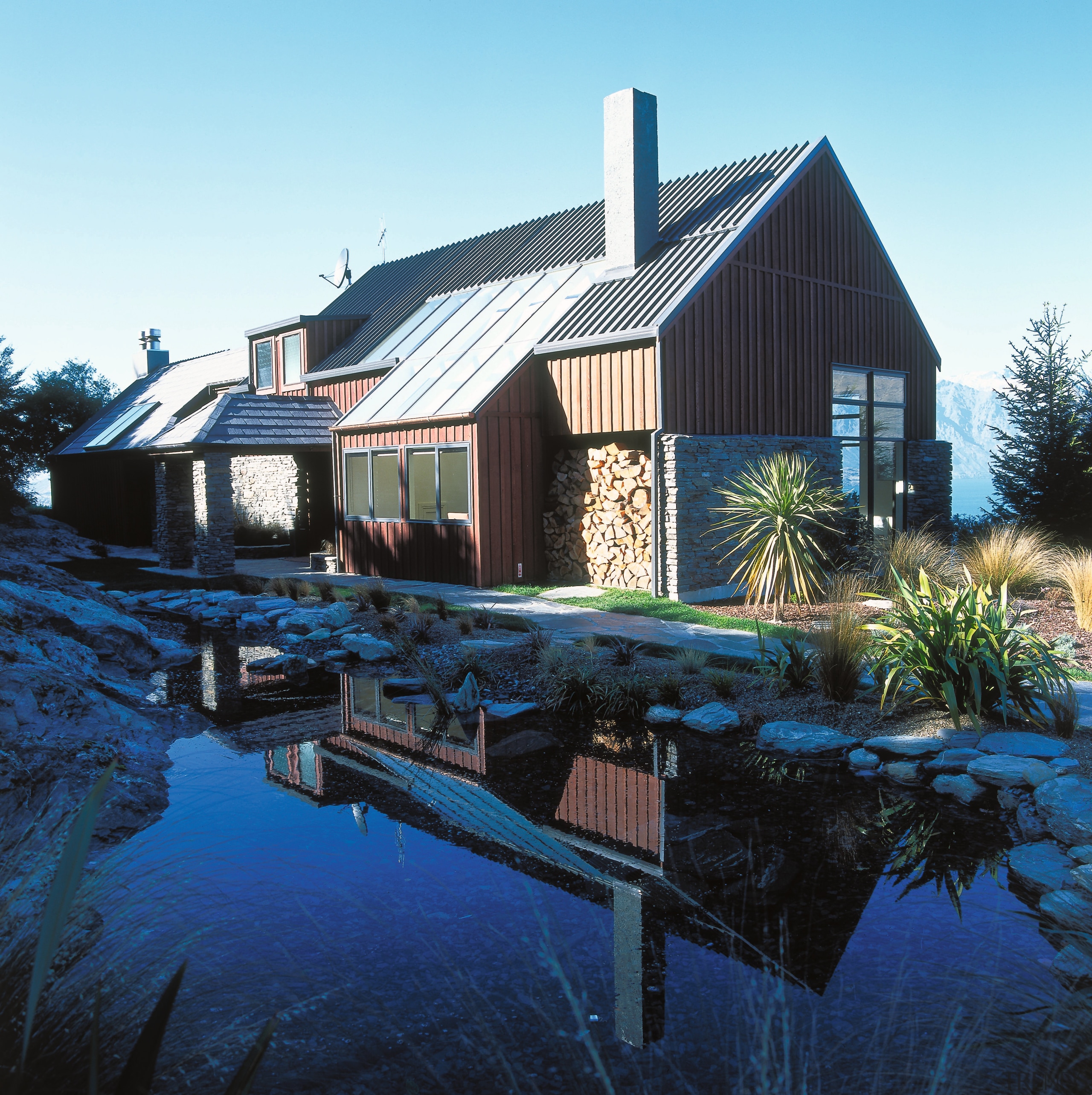 view of the azura lodge featuring pleanty of architecture, cottage, estate, farmhouse, home, house, hut, property, real estate, reflection, residential area, roof, shed, siding, sky, water, blue, black