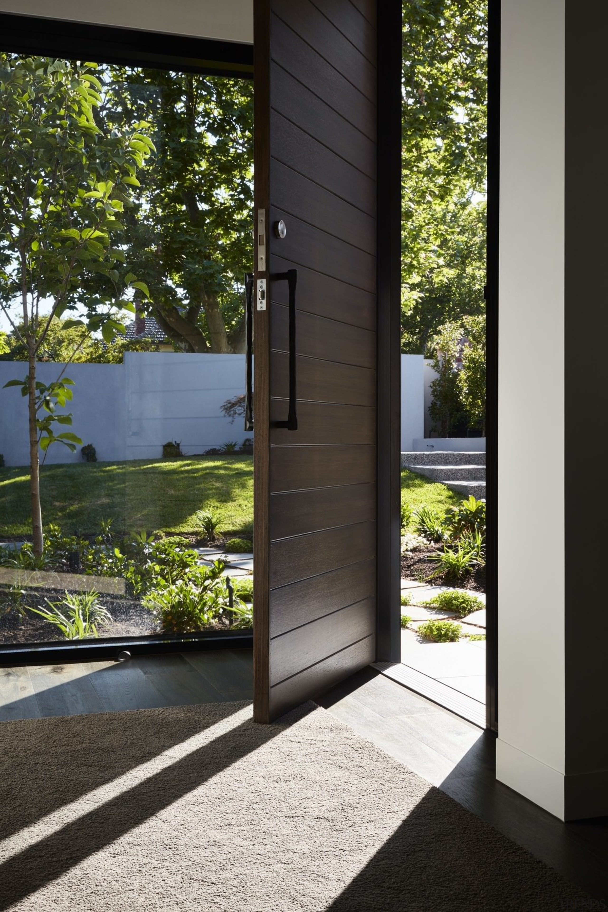 A floor to ceiling window sits alongside this architecture, door, home, house, window, wood, black