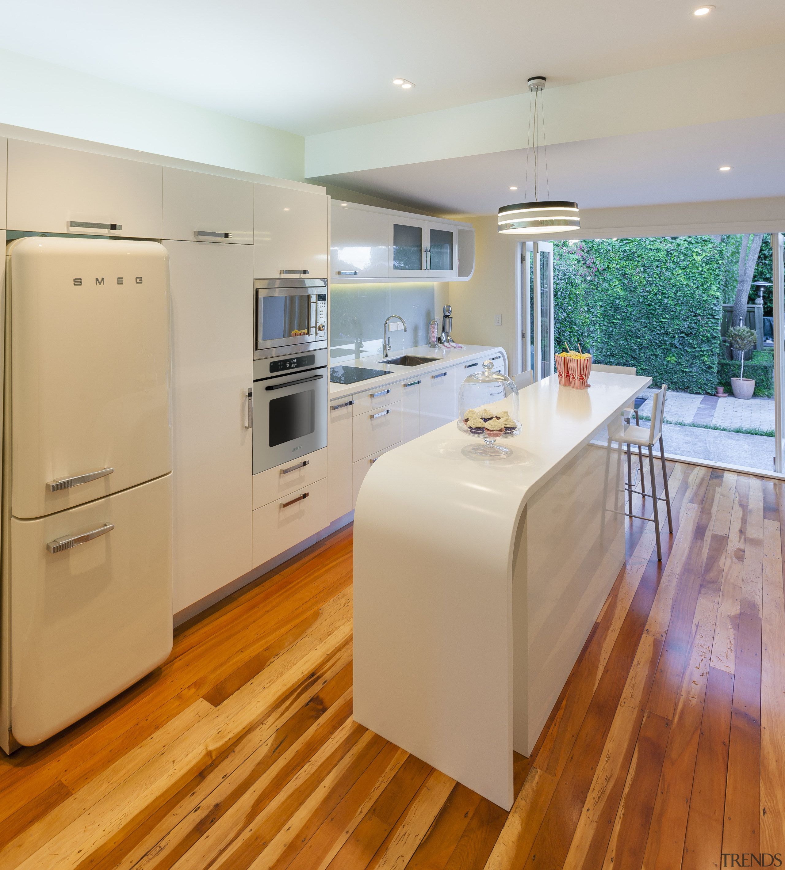 Contemporary kitchen with curved white island and wooden cabinetry, countertop, floor, flooring, hardwood, interior design, kitchen, laminate flooring, real estate, room, wood flooring, gray, orange