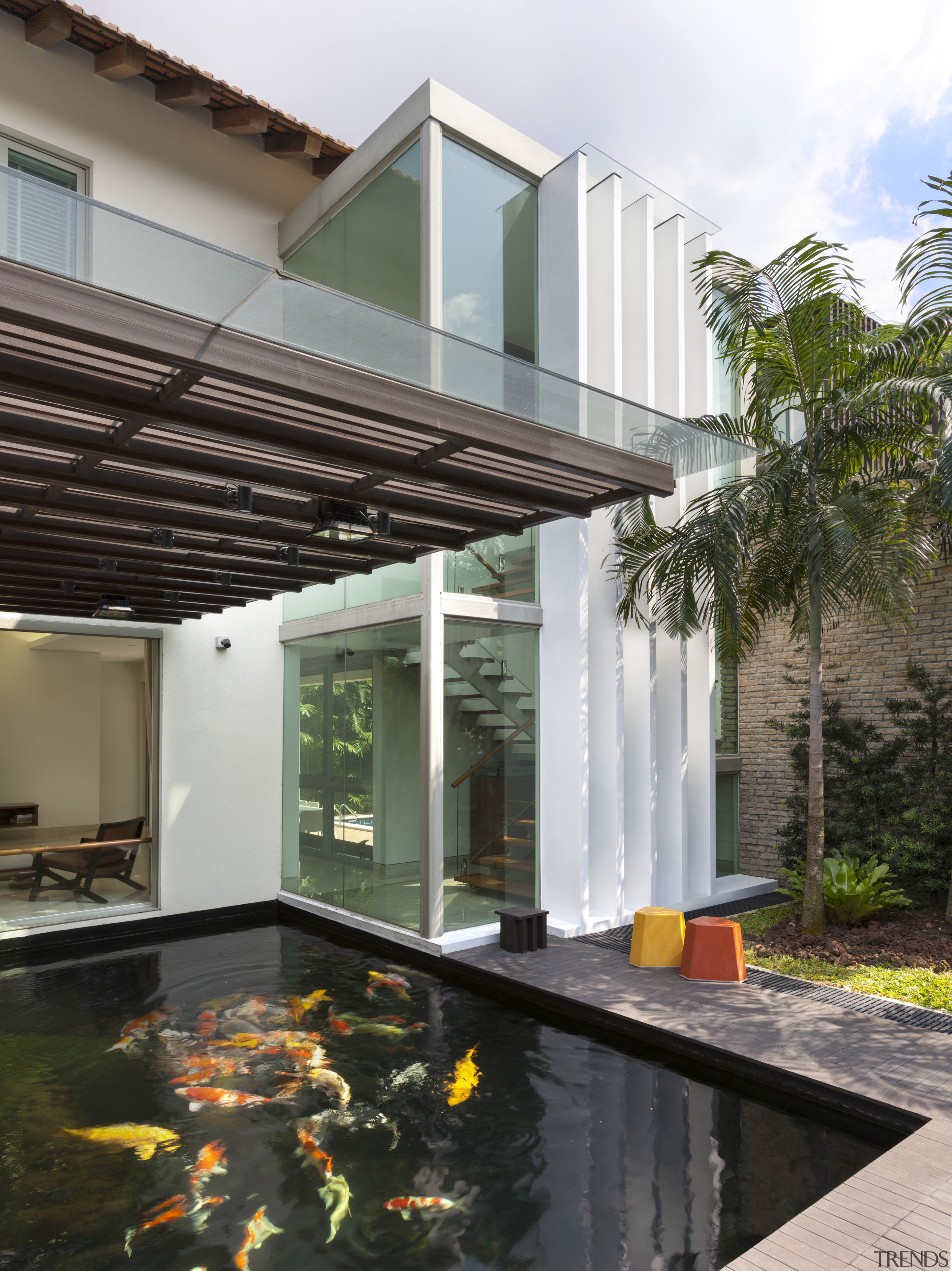 A fully glazed stairwell overlooks the koi pond architecture, facade, home, house, property, real estate, swimming pool, black, white