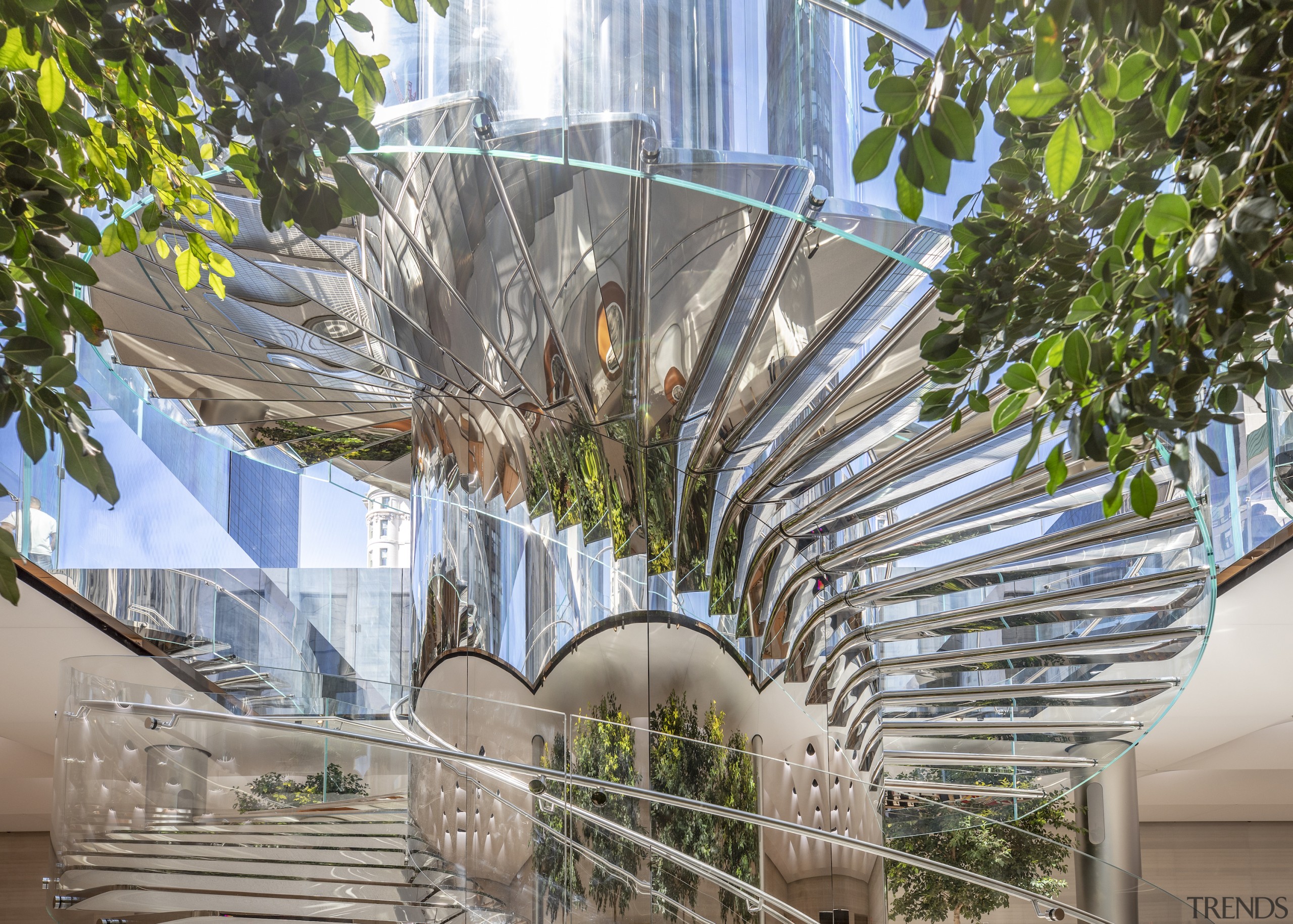 Visitors descend under the light-flooded glass cube, down gray