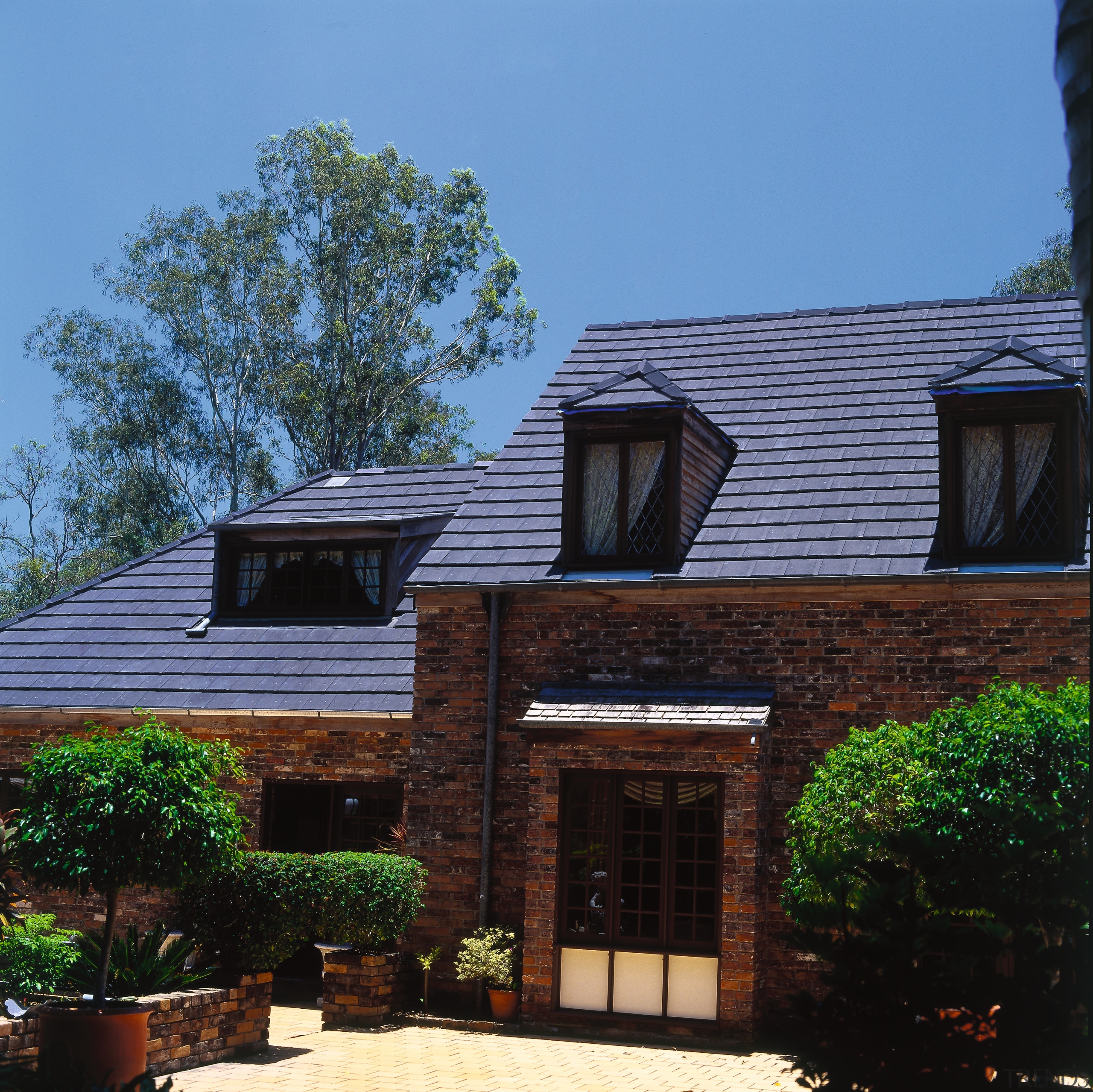 Exterior of house with brick cladding, steep pitched architecture, cottage, estate, facade, home, house, outdoor structure, property, real estate, residential area, roof, siding, window, black, teal