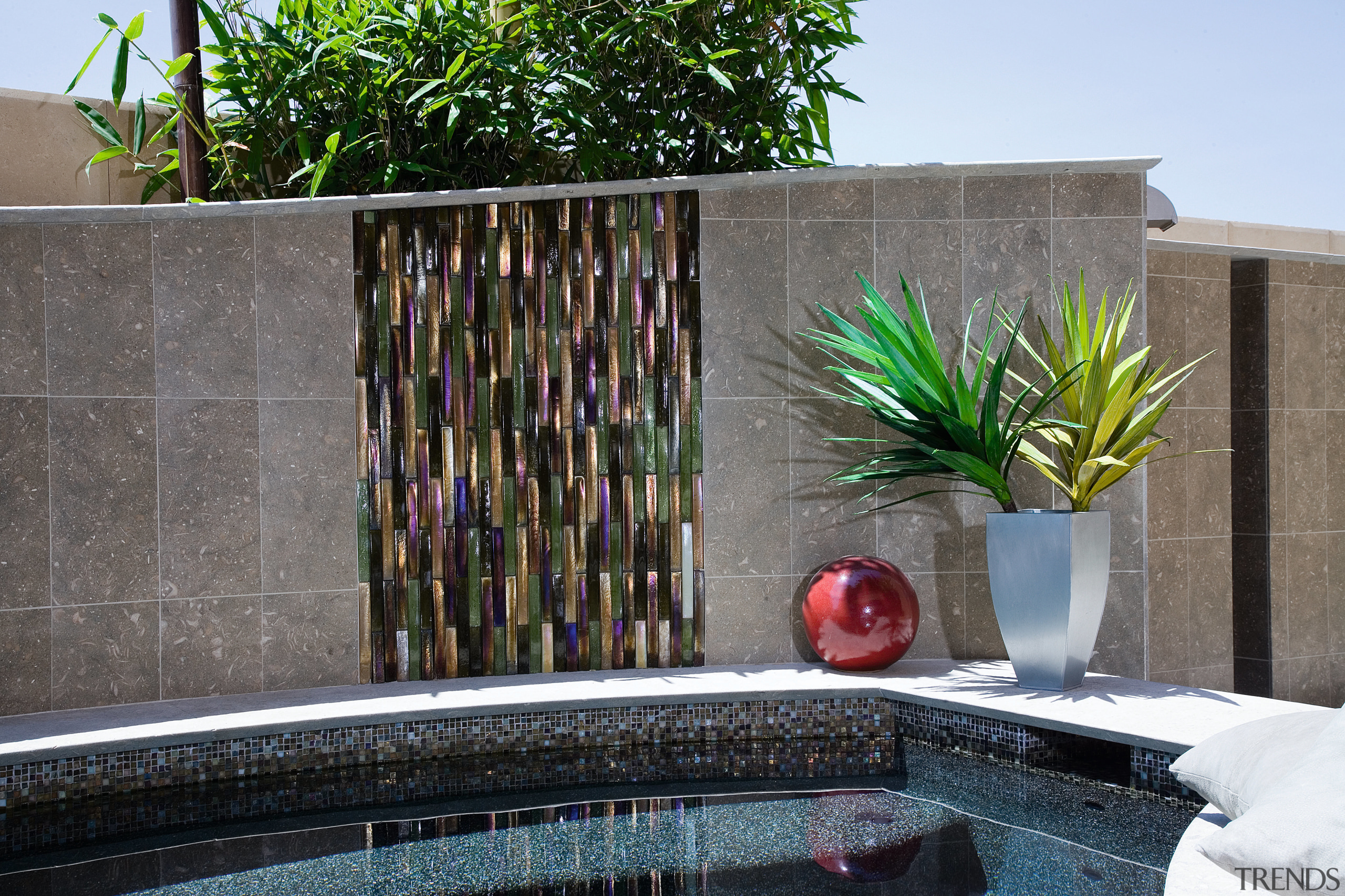 Glaas tiles were laid horizontally to create an arecales, palm tree, plant, property, swimming pool, wall, water, water feature, gray