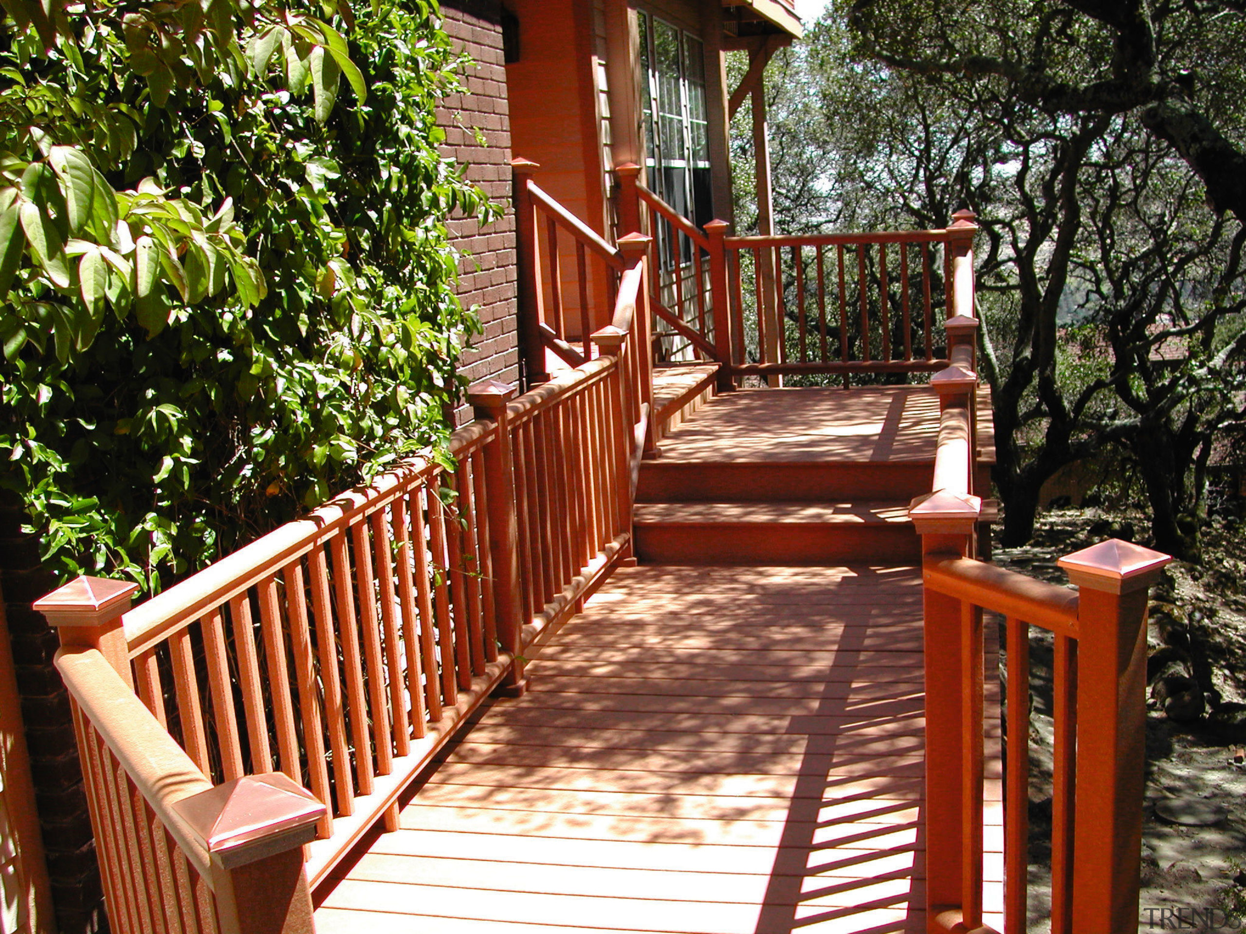 Exterior view of a wooden decking system and backyard, cottage, deck, handrail, home, house, outdoor structure, plant, property, real estate, tree, walkway, wood, yard, red