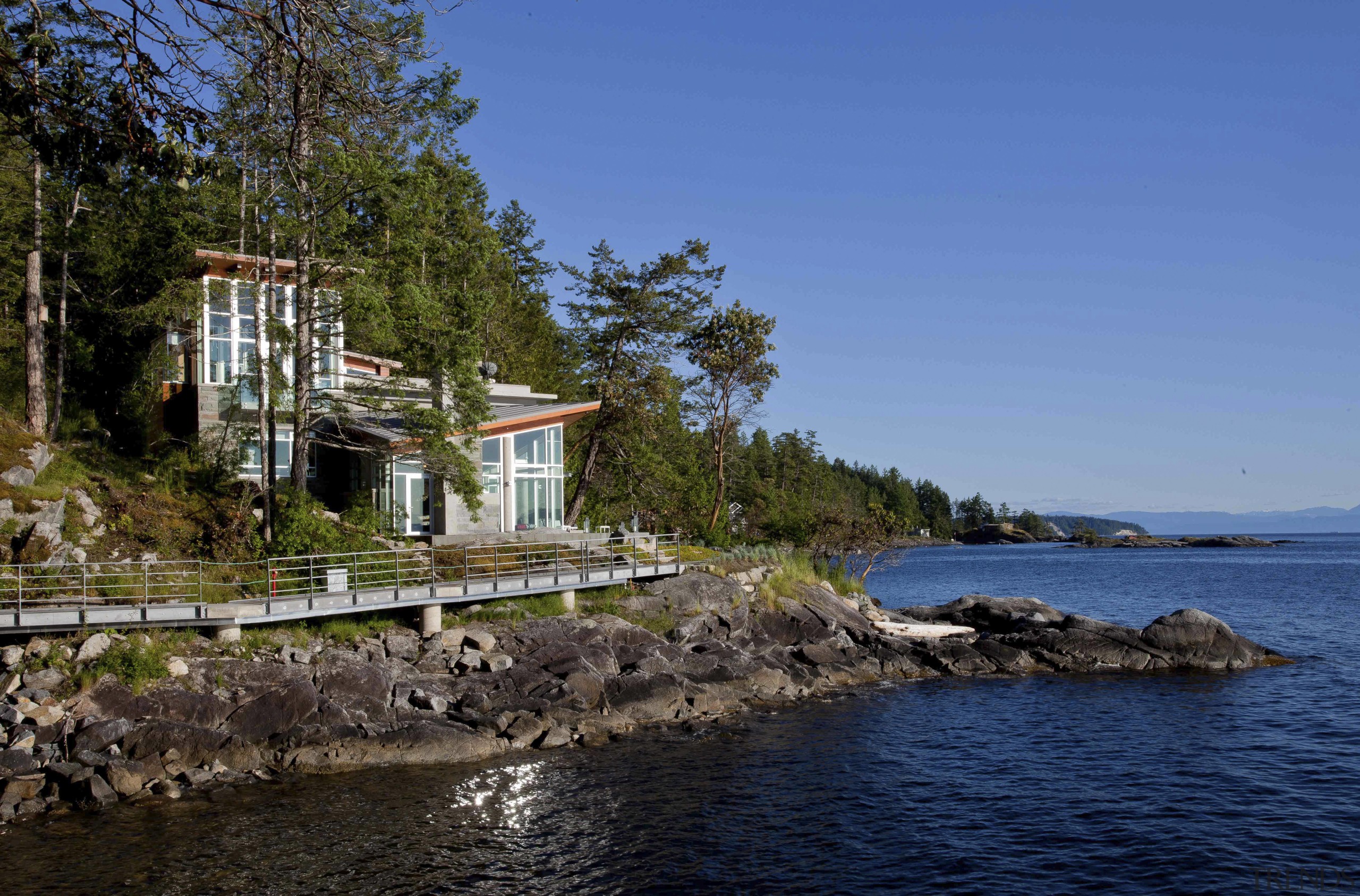 View of waterfront house. - View of waterfront bay, coast, cottage, home, house, inlet, lake, real estate, sea, shore, sky, tree, water, blue
