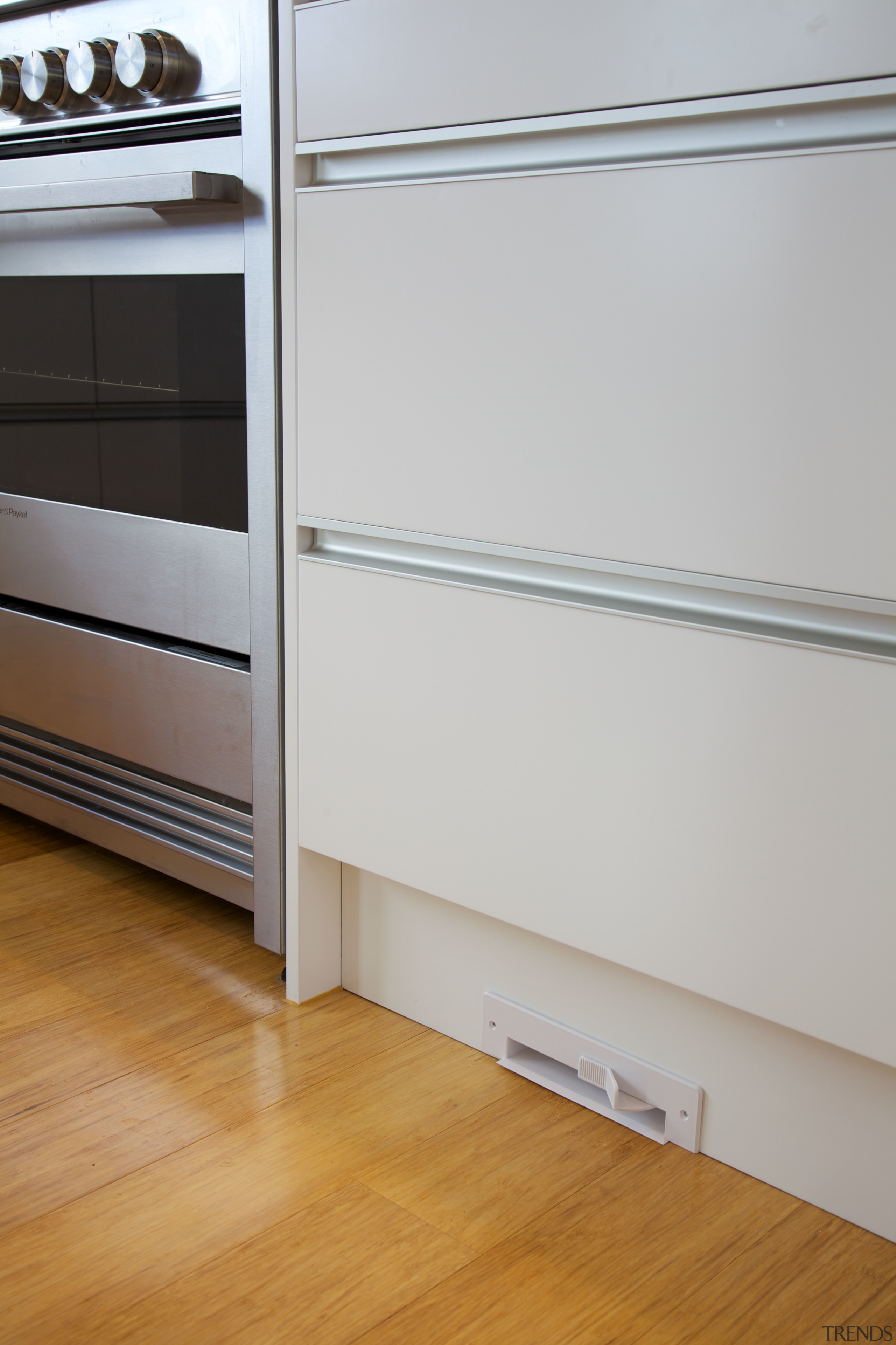 A vacuum vent in the kitchen can be cabinetry, chest of drawers, drawer, floor, flooring, furniture, hardwood, laminate flooring, room, wall, wood, wood flooring, gray