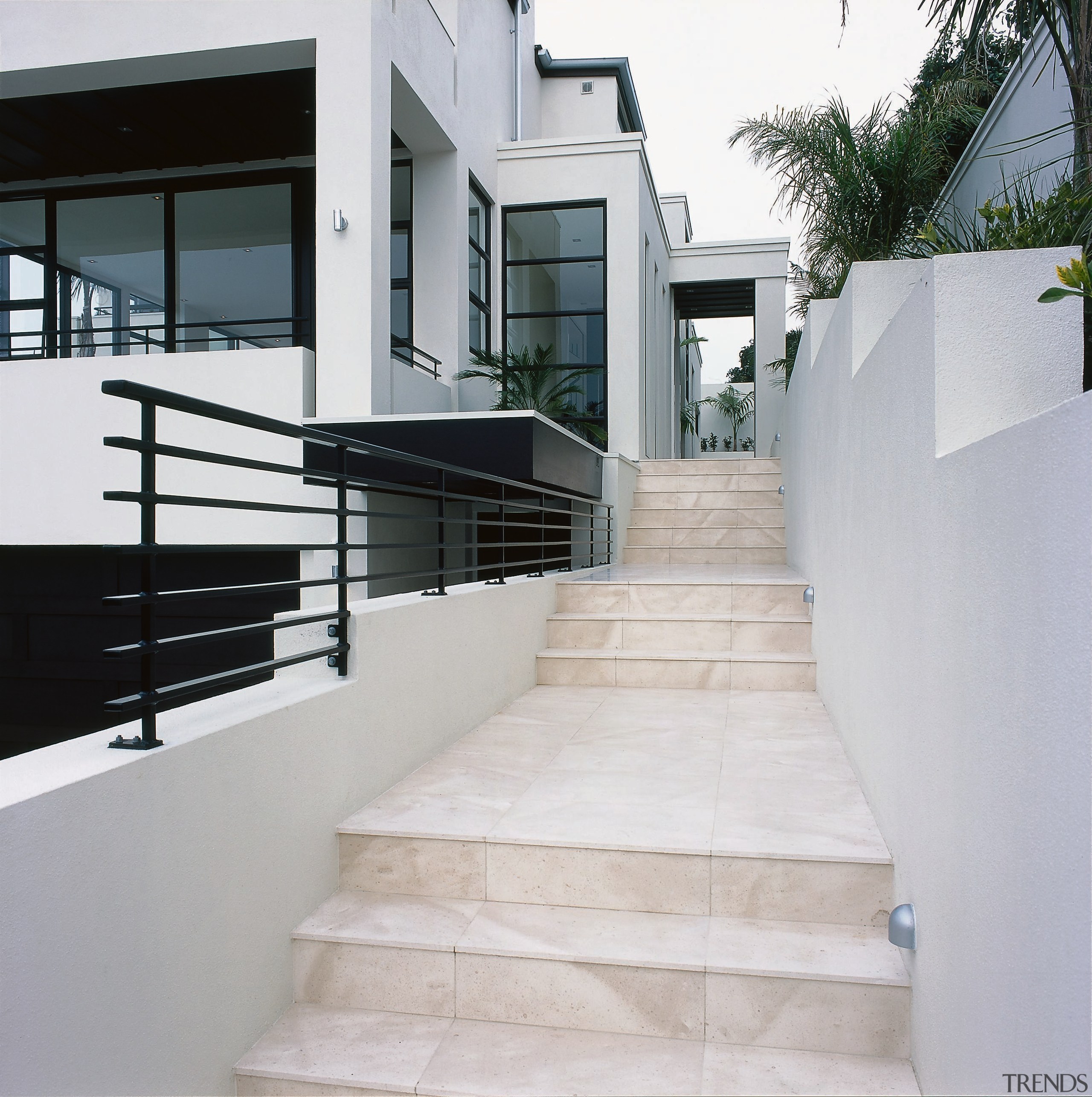 A stairway featuring coffee-coloured limestone tiles. The stairway apartment, architecture, handrail, home, house, stairs, gray