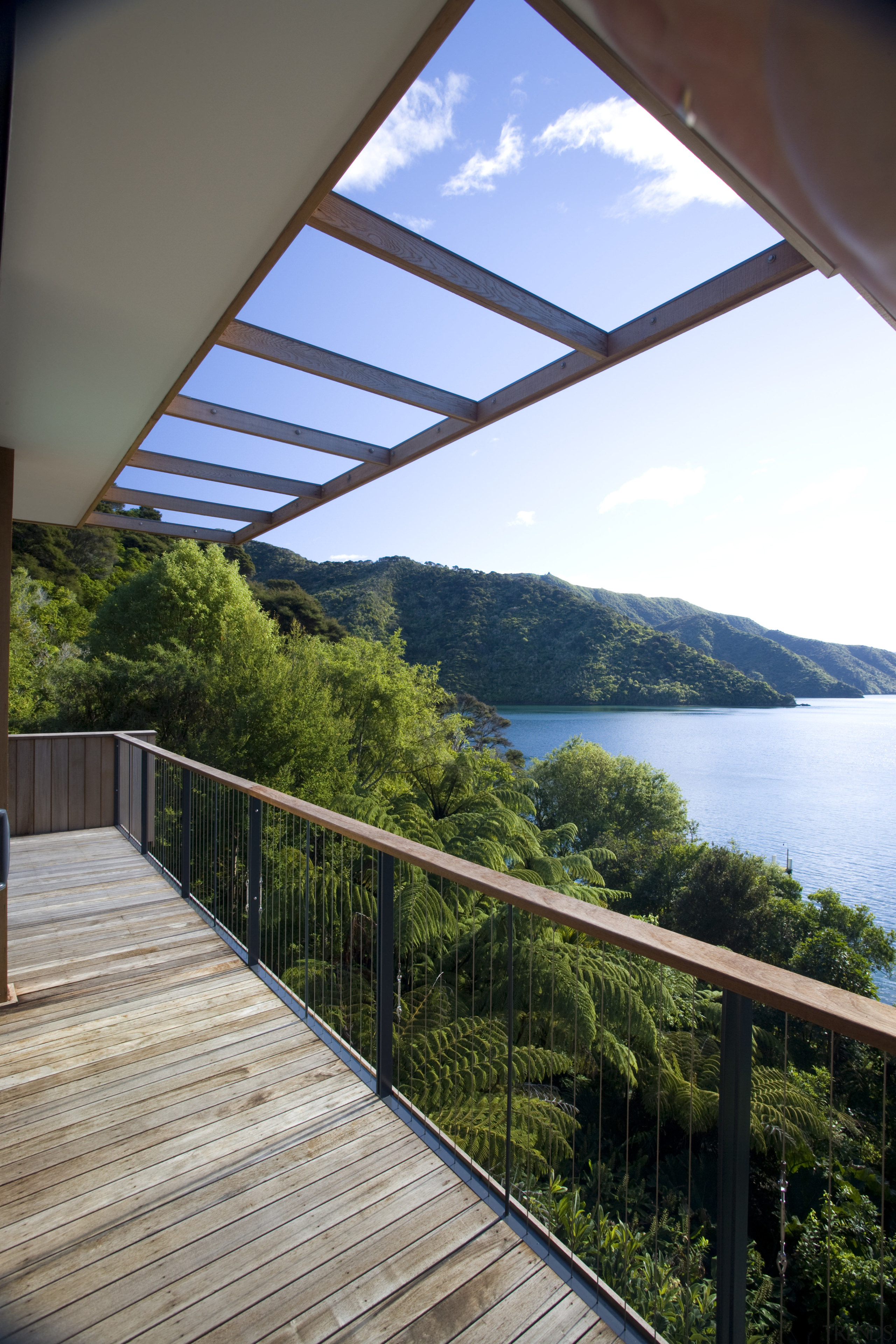 View of deck and side of house with apartment, architecture, balcony, daylighting, estate, handrail, home, house, outdoor structure, property, real estate, reflection, sky, window, gray