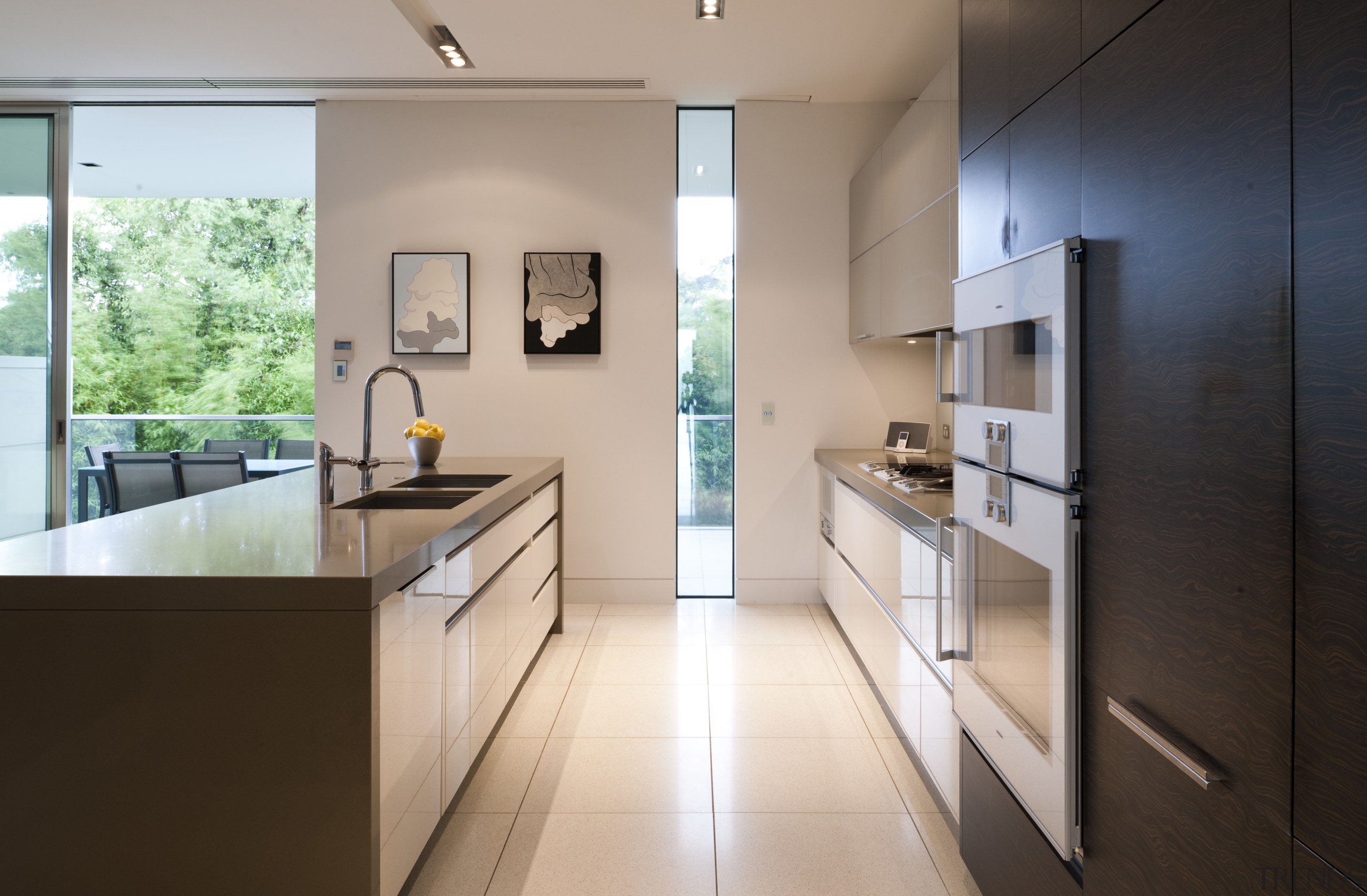 View of contemporary kitchen with light toned flooring, architecture, countertop, floor, house, interior design, kitchen, real estate, gray, black