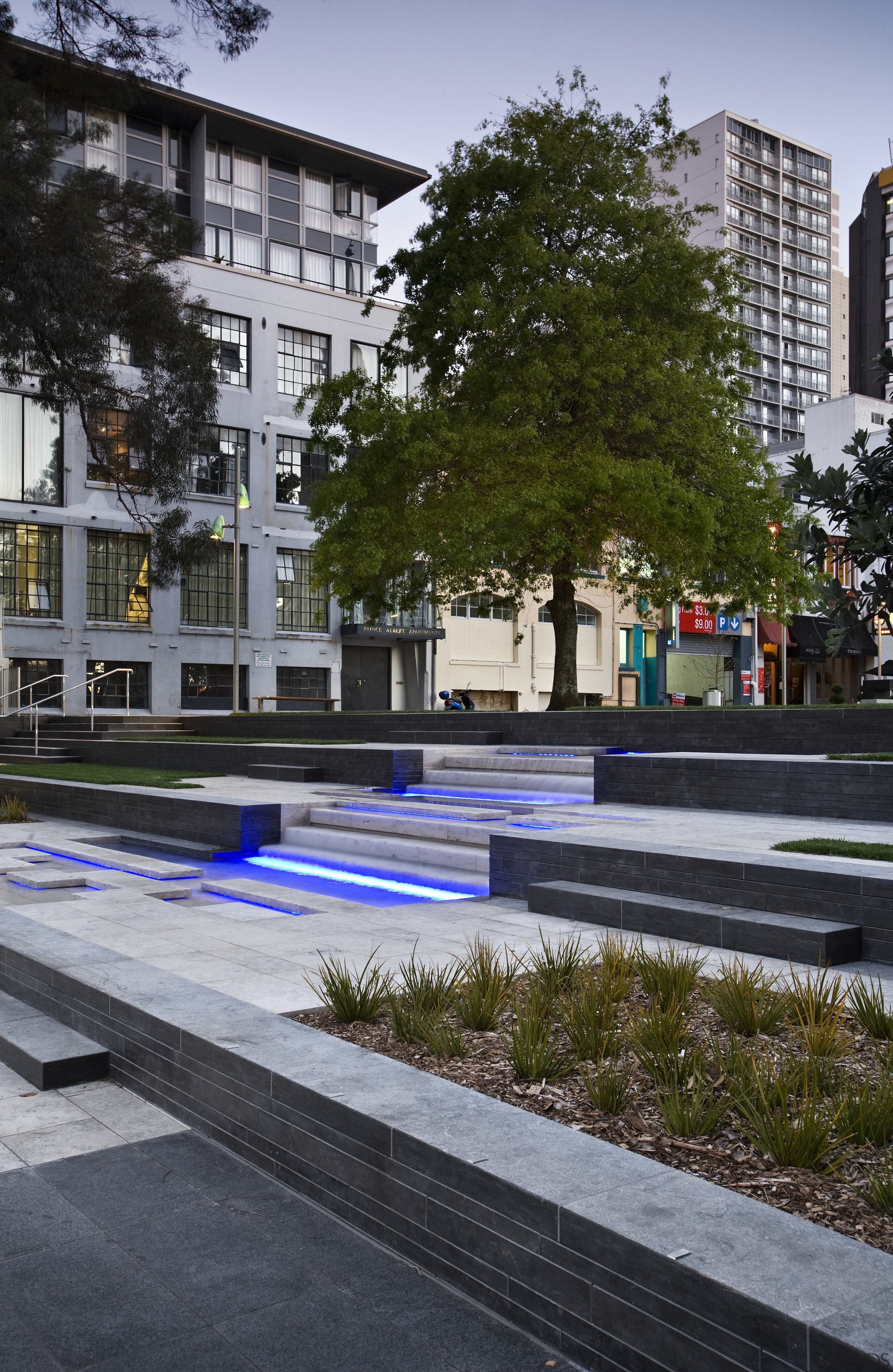 View of St Patrick's square featuring landscaping, paving, architecture, building, city, condominium, daytime, downtown, metropolitan area, mixed use, neighbourhood, plant, plaza, reflection, residential area, tree, urban area, urban design, gray, black