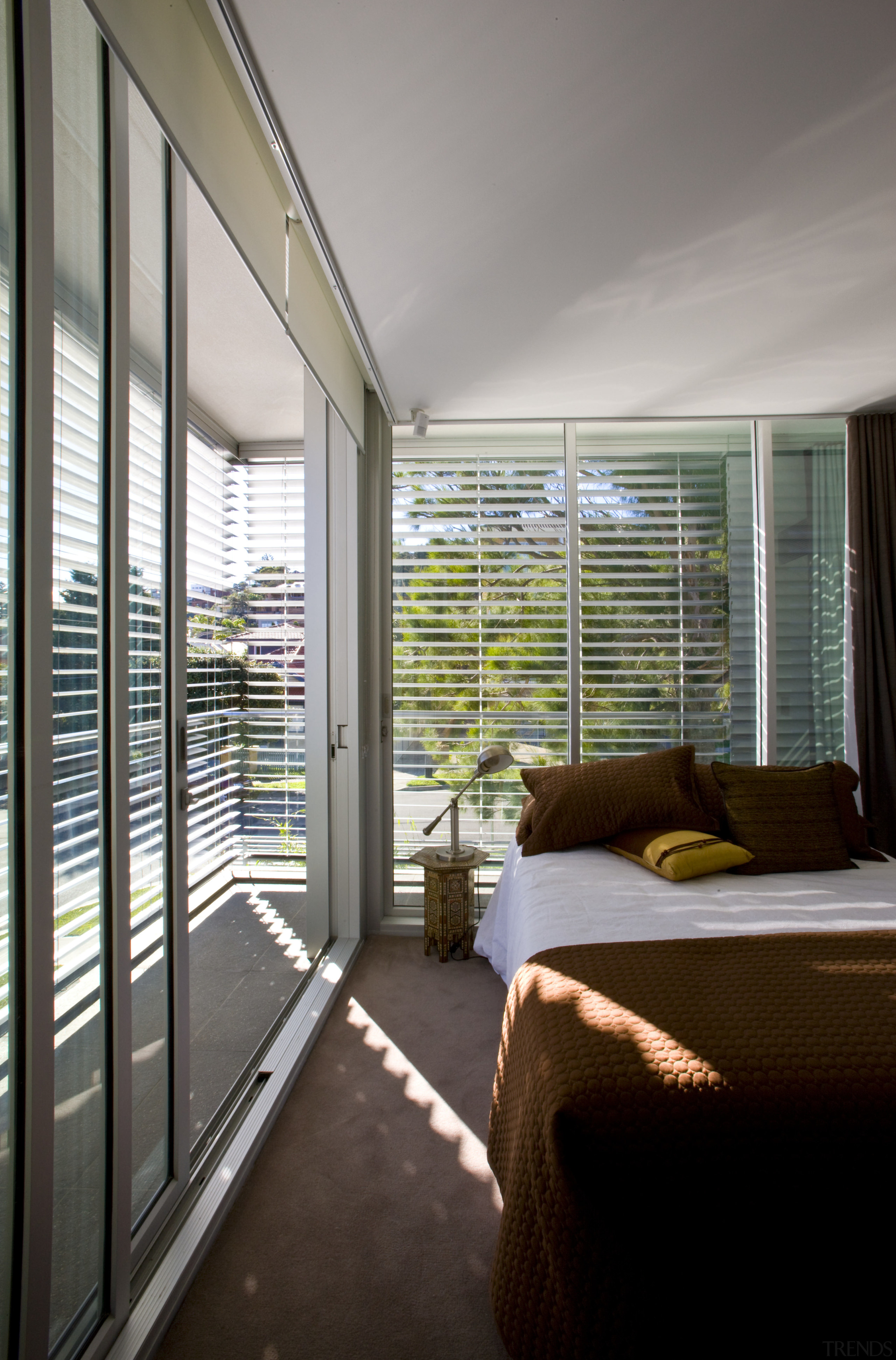 View of bedroom which features bed with brown architecture, balcony, ceiling, condominium, daylighting, door, home, house, interior design, real estate, shade, window, window blind, window covering, window treatment, wood, gray, black