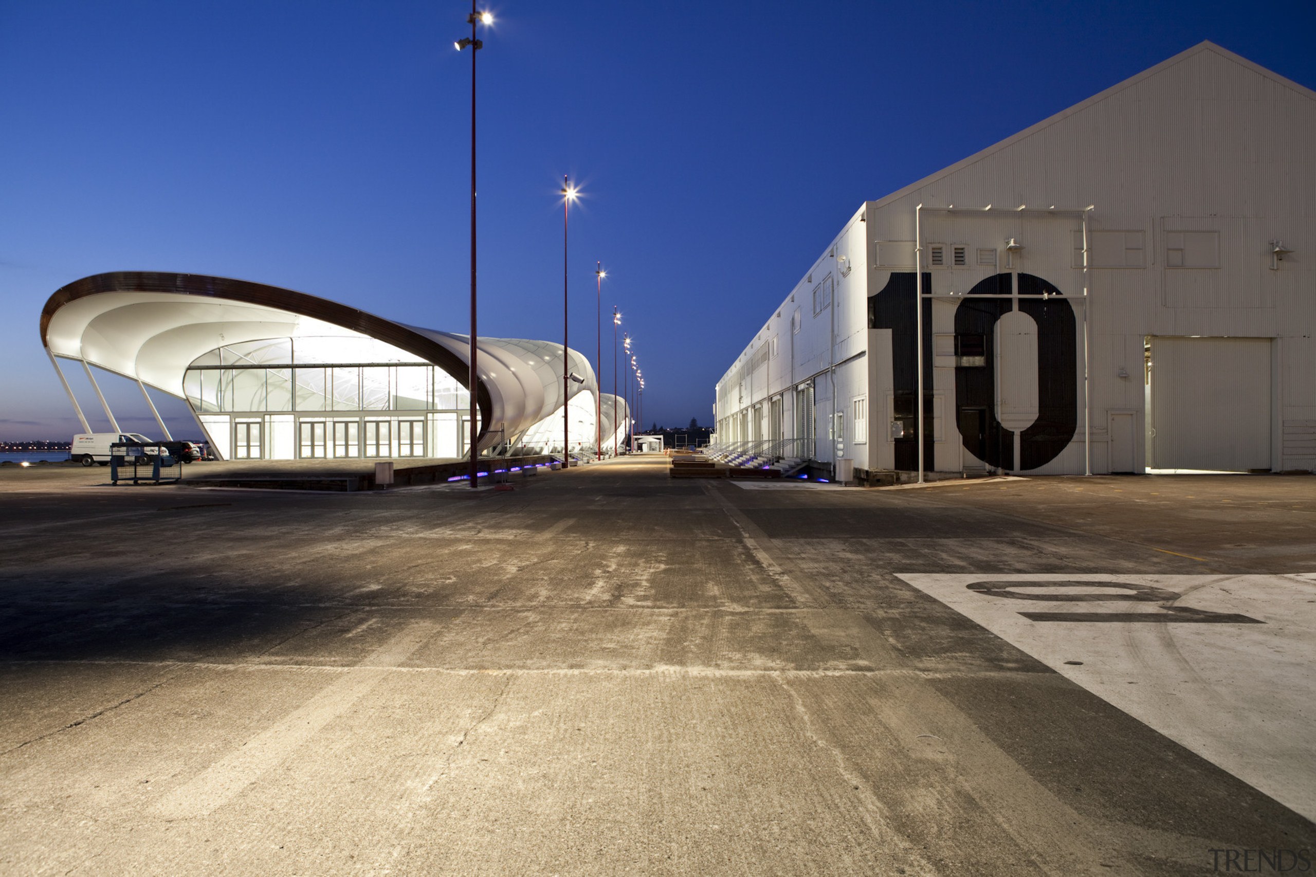 Waterfront building at night with lights on. - architecture, asphalt, building, fixed link, infrastructure, sky, structure, blue