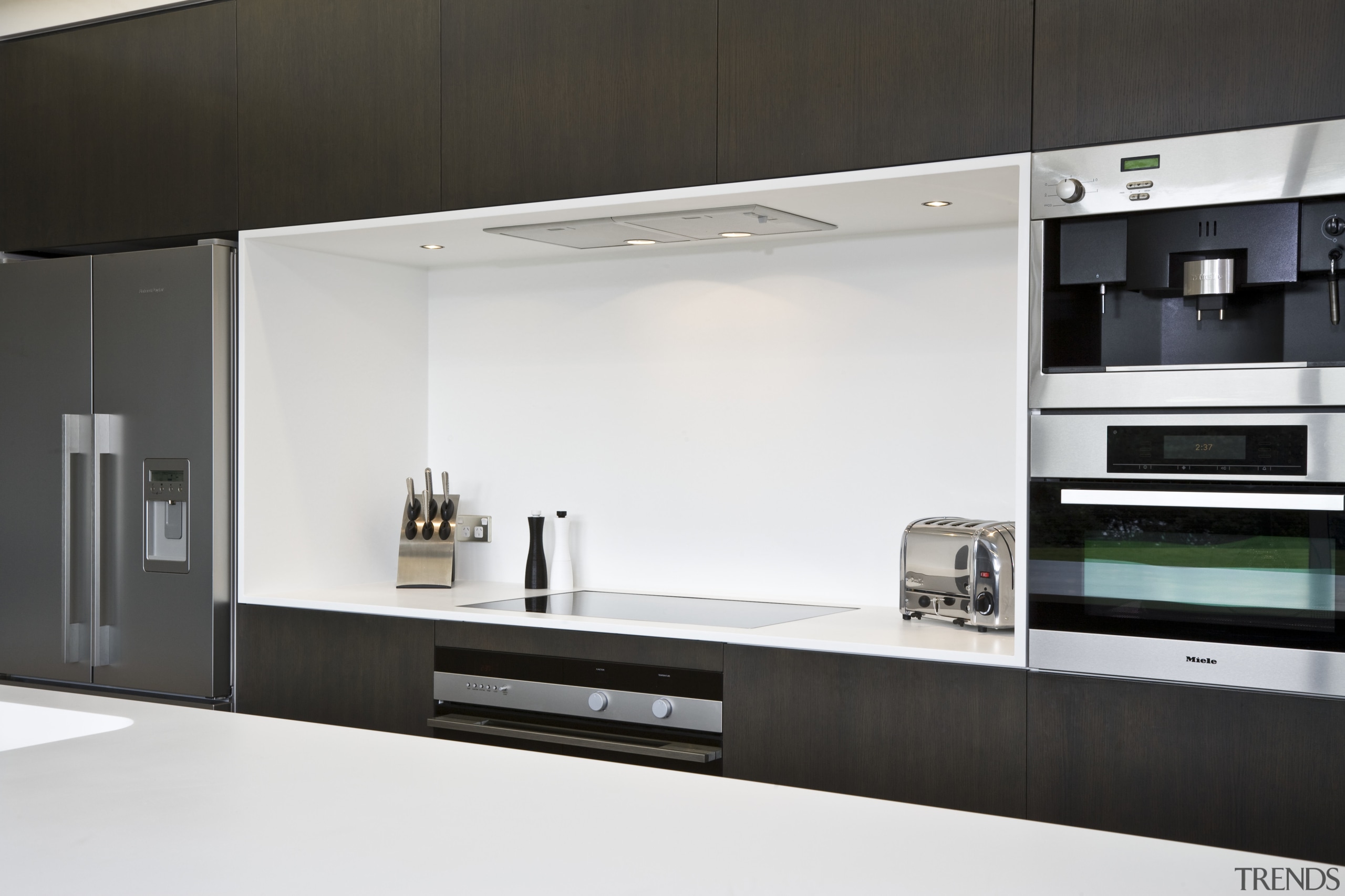 View of kitchen featuring dark-stained oak cabinetry, appliances, countertop, home appliance, interior design, kitchen, product design, white, black