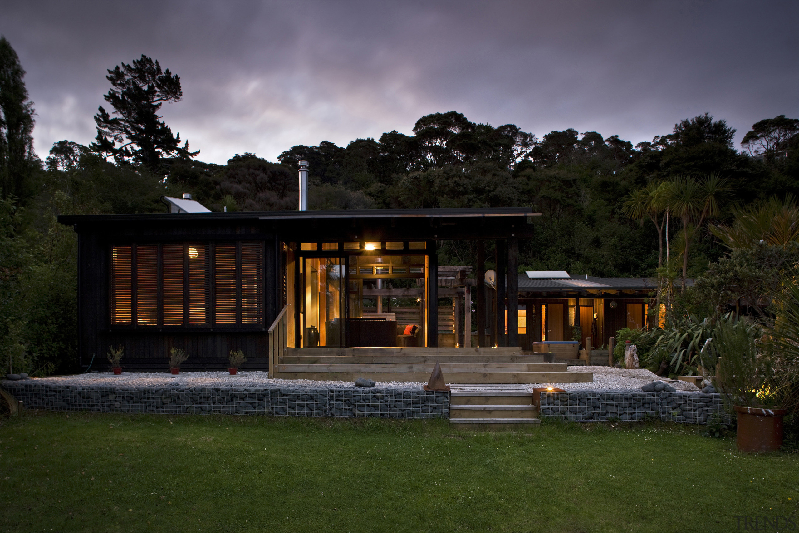 The timber for this house is treated with architecture, backyard, cloud, cottage, estate, evening, facade, farmhouse, home, house, landscape, lighting, night, real estate, residential area, shed, sky, tree, black, brown