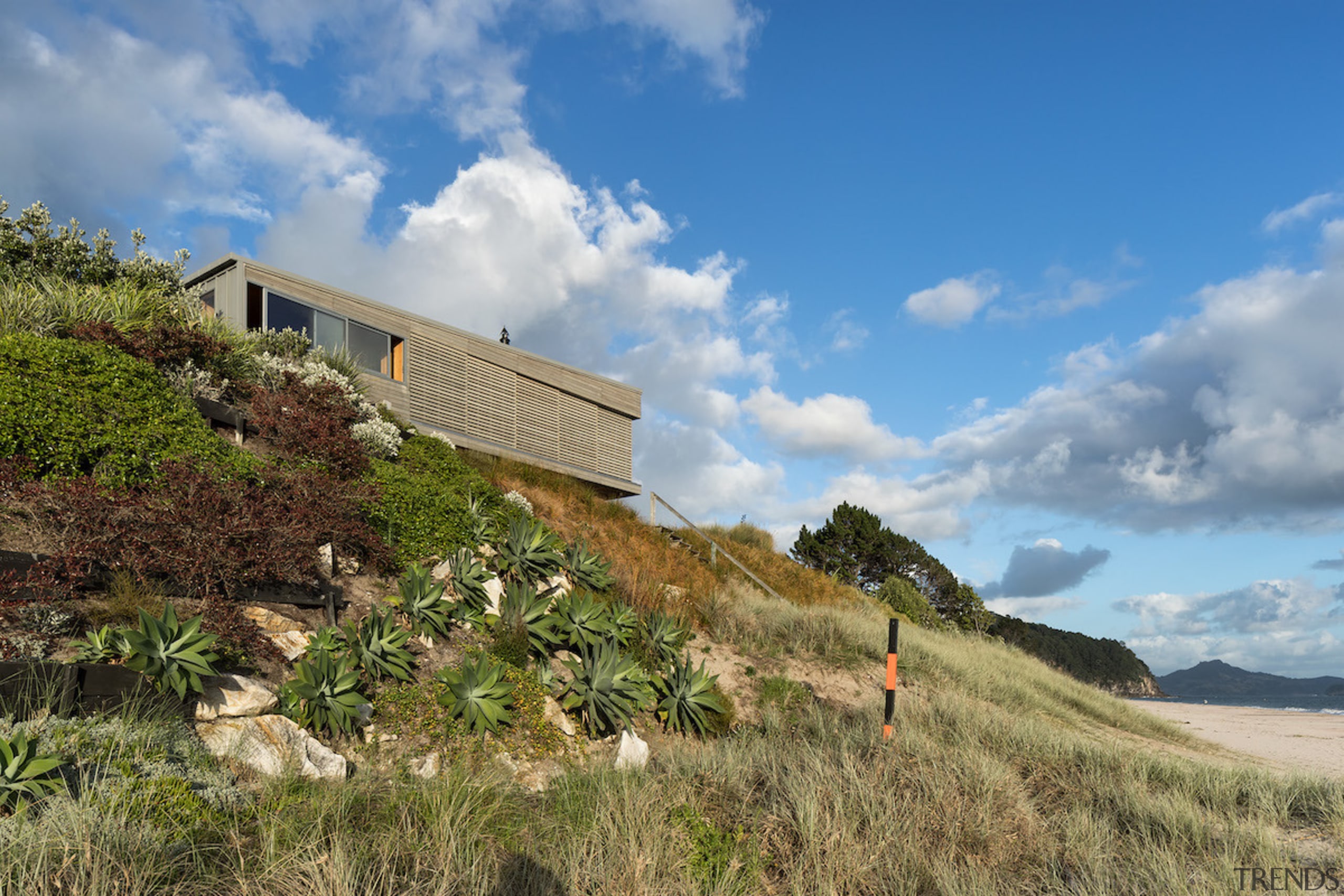 Studio2 Architects, designed this two-level beach house on architecture, cloud, cottage, grass, hill, home, house, land lot, landscape, mountain, property, real estate, rural area, sky, terrain, tree, teal, brown