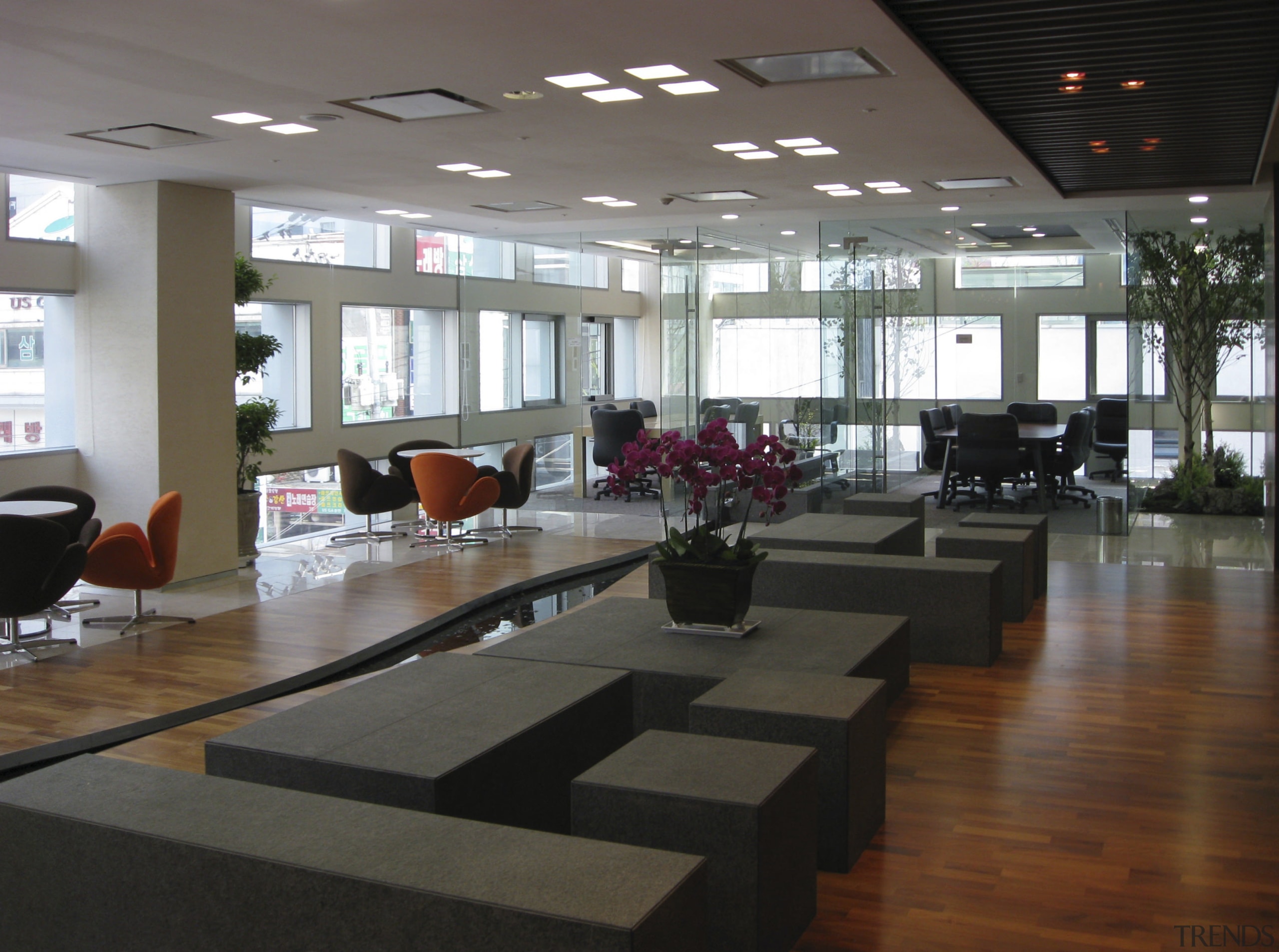 Wooden flooring, grey seating, vase of purple flowers. floor, flooring, furniture, interior design, lobby, black, gray