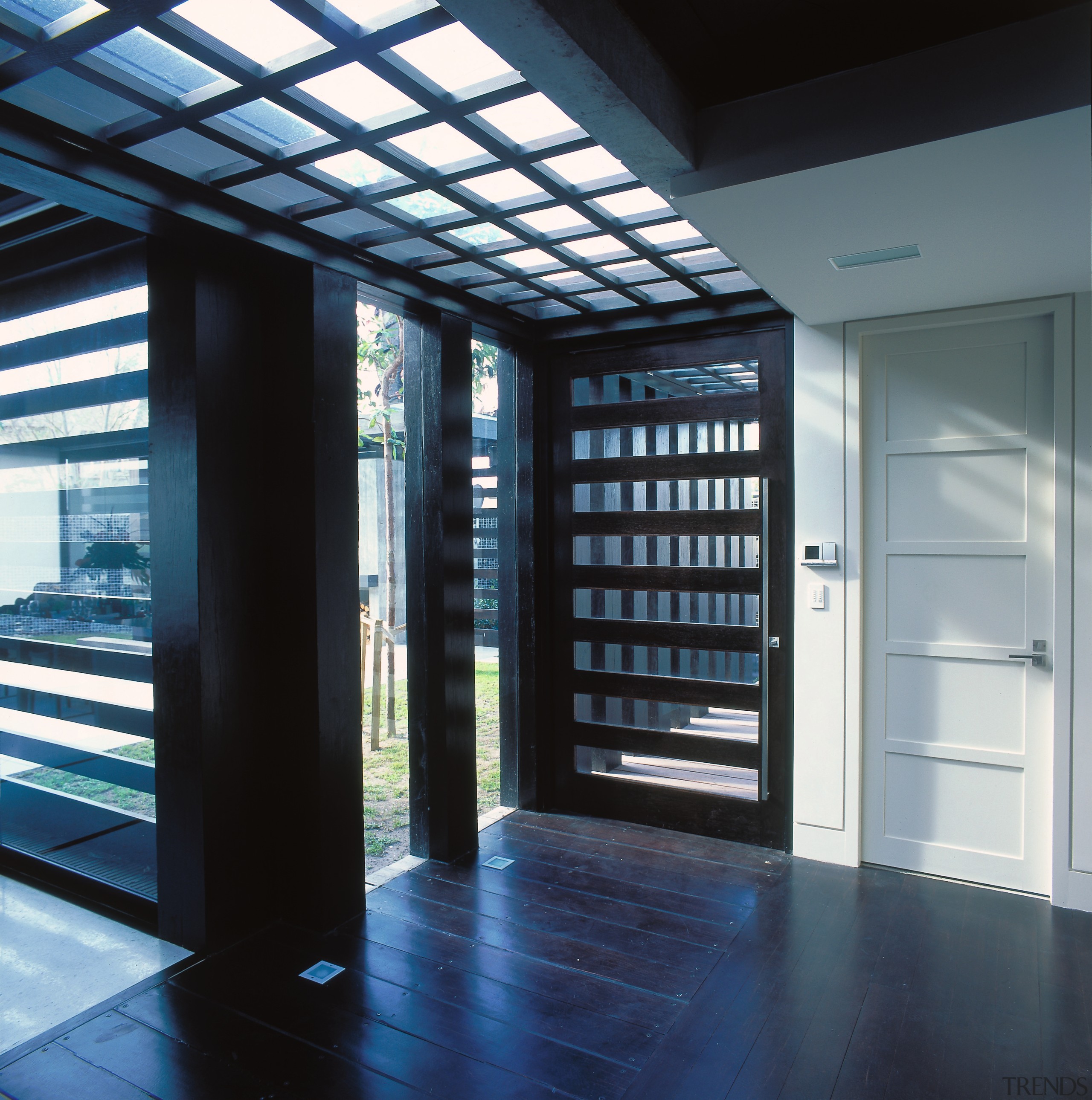 view of the slatted entrance featuring dark stained daylighting, door, window, black
