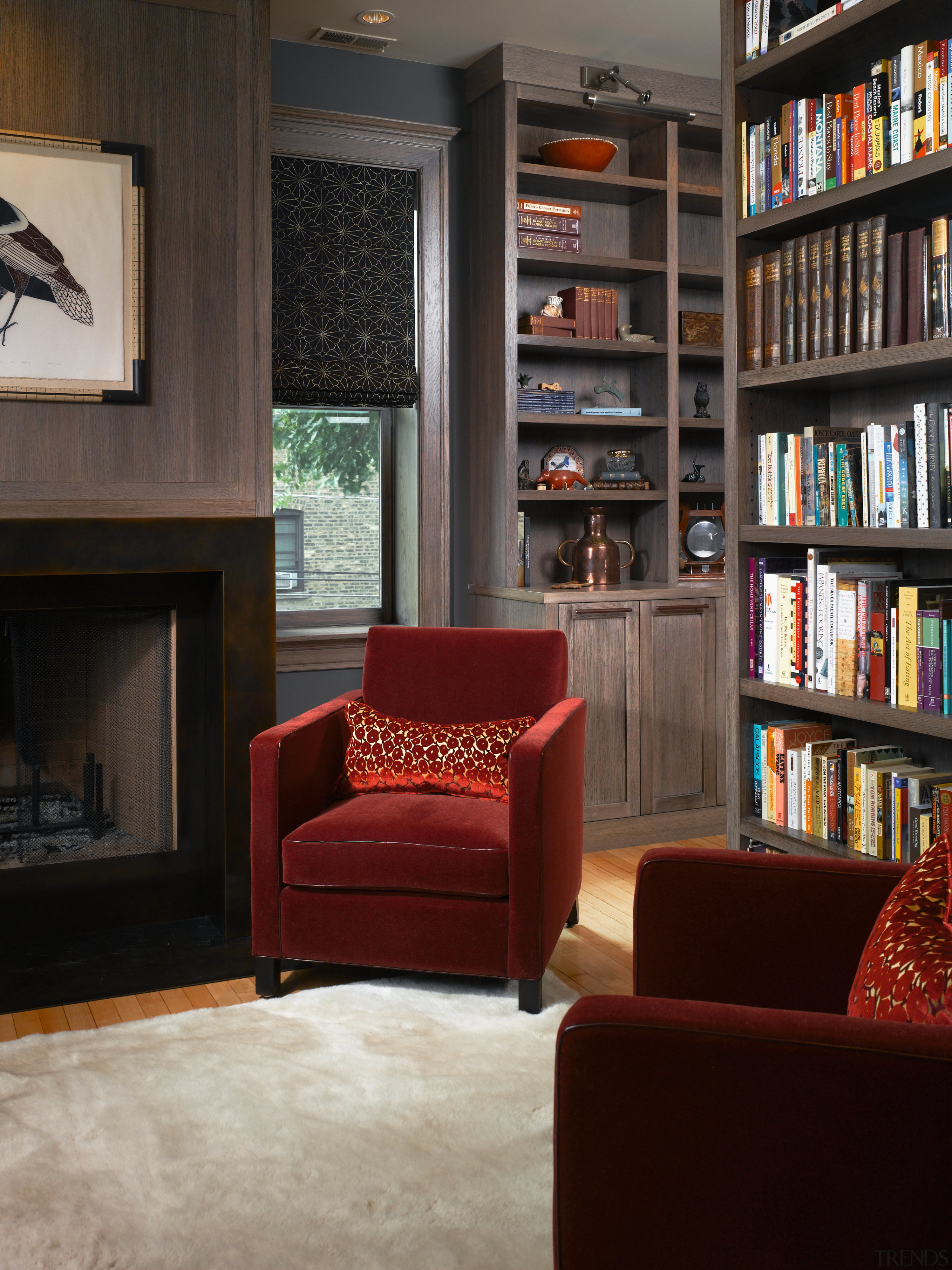 A view of this living area featuring red bookcase, floor, flooring, furniture, home, interior design, library, living room, shelf, shelving, black, gray