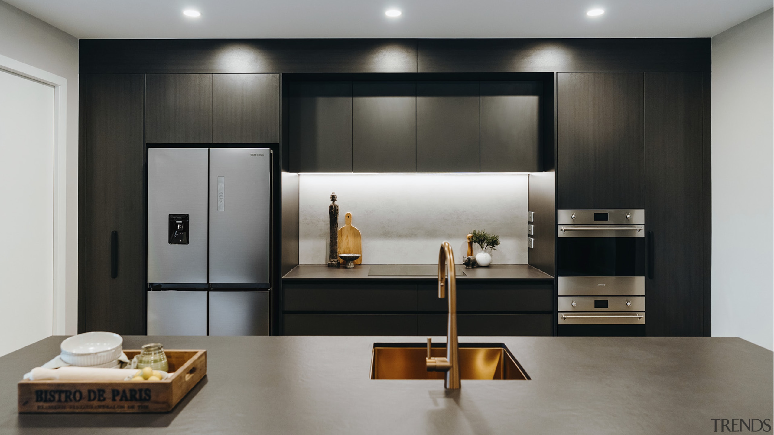 Dark, dramatic cabinetry, a designer brass sink and 